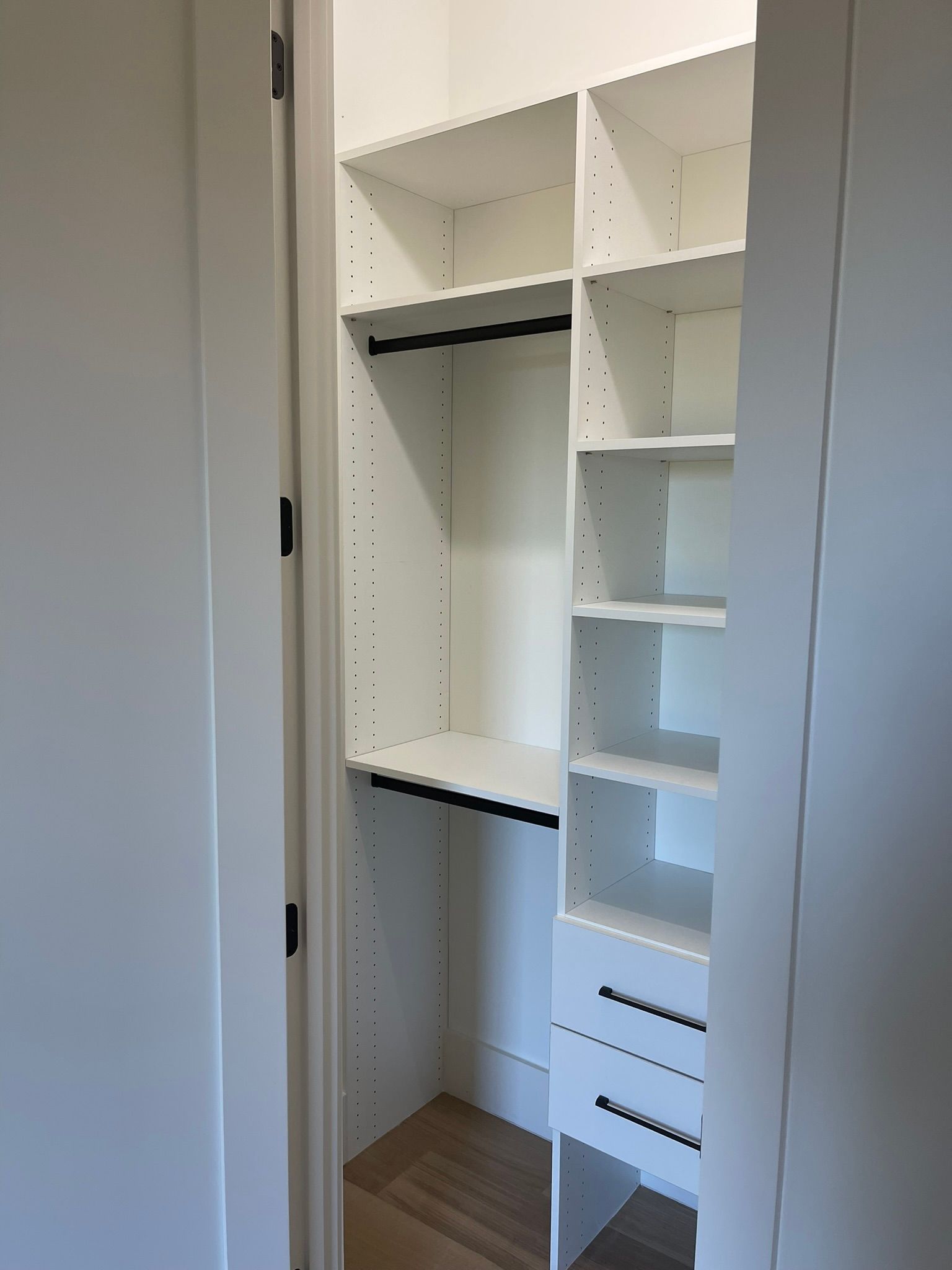 White closet with shelves, drawers, and hanging rods. Interior view.
