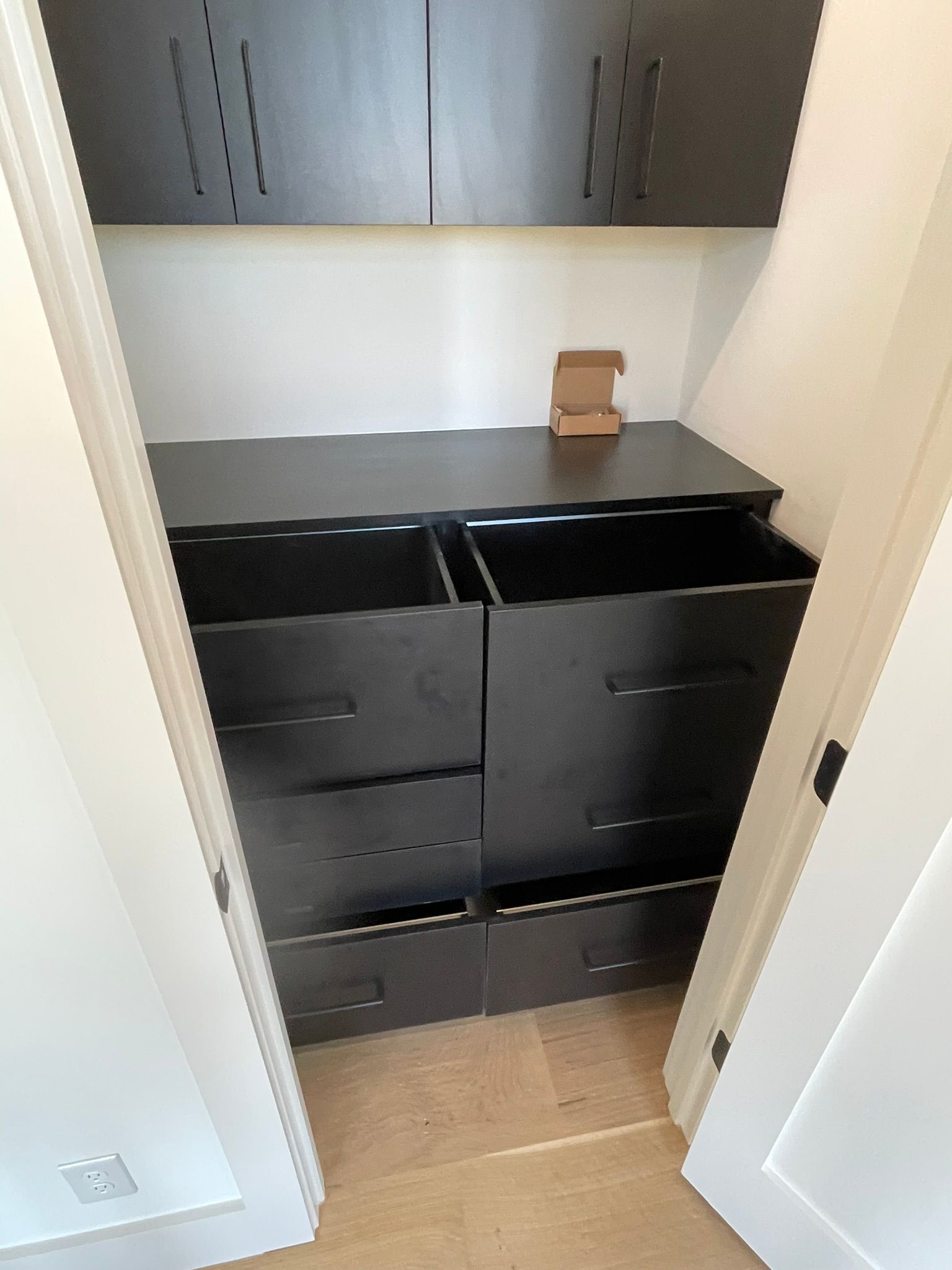 Black storage unit with drawers inside a closet.