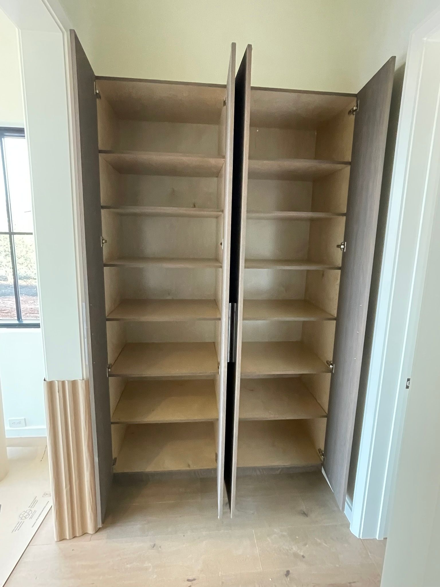 Open, empty cabinet with multiple shelves; light-colored wood inside, white and wood trim.