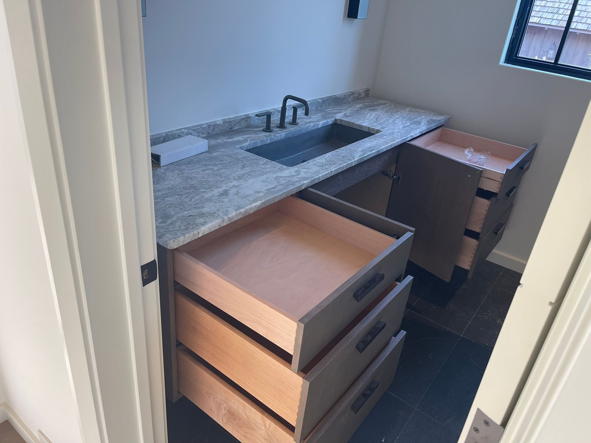 Bathroom with gray countertop, sink, open drawers, and a cabinet.