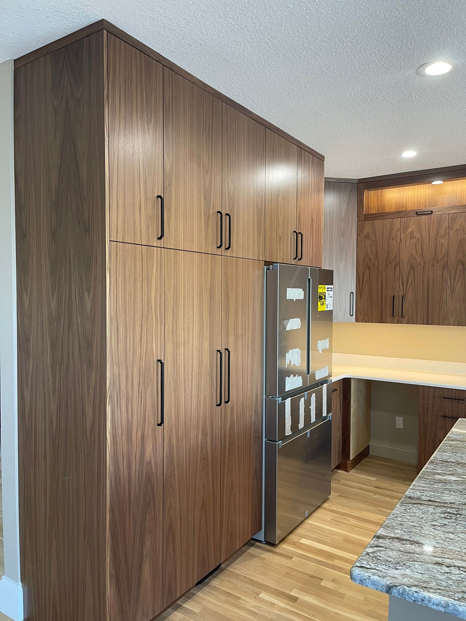 Tall wooden cabinets and a stainless steel refrigerator in a kitchen setting.