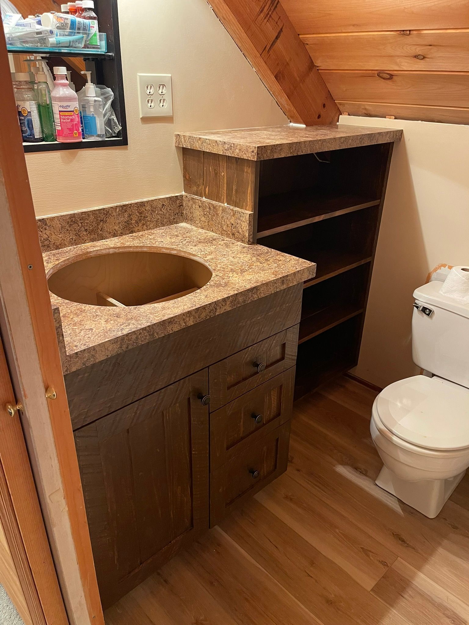 Bathroom with a sink, cabinet, open shelving unit, and toilet.