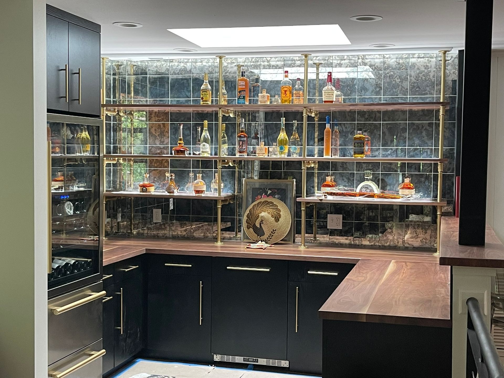 Modern home bar with black cabinets, wood countertops, and liquor display shelves.