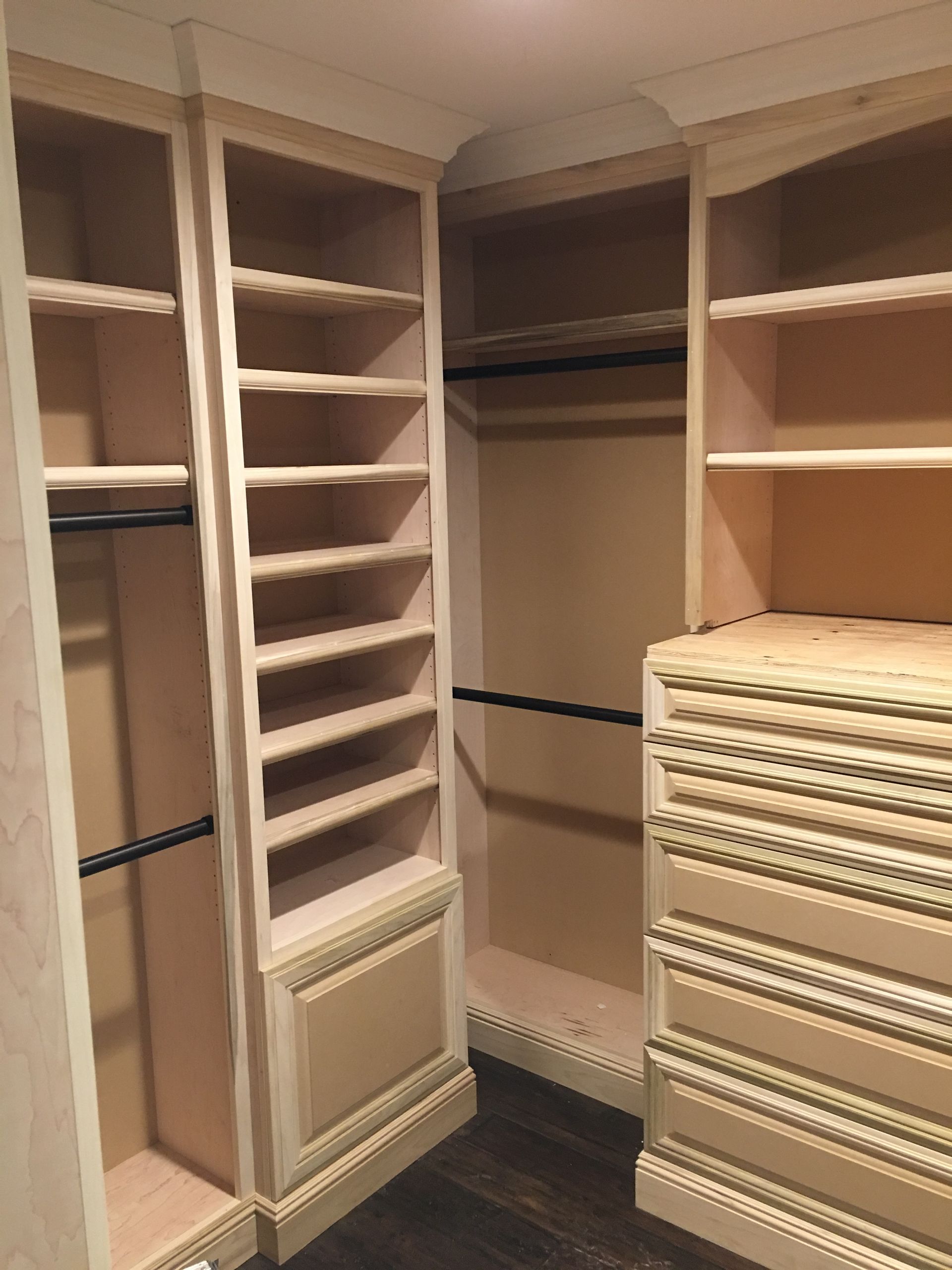 Built-in closet with shelves and hanging rods. Light-colored wood construction. Dark flooring.