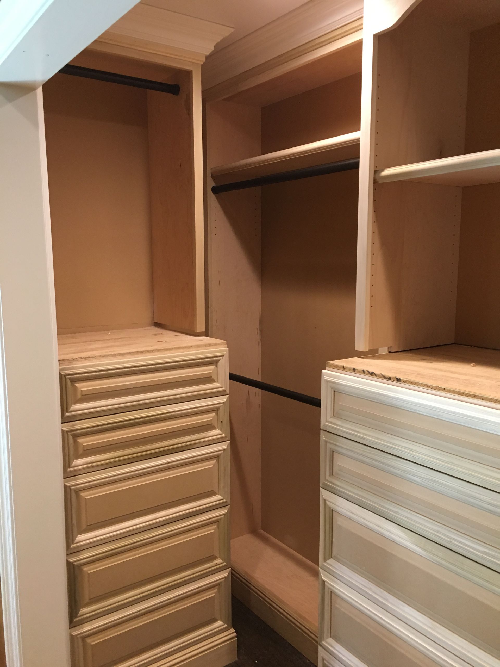 Wooden closet with drawers, shelves, and hanging rods. Light-colored wood.