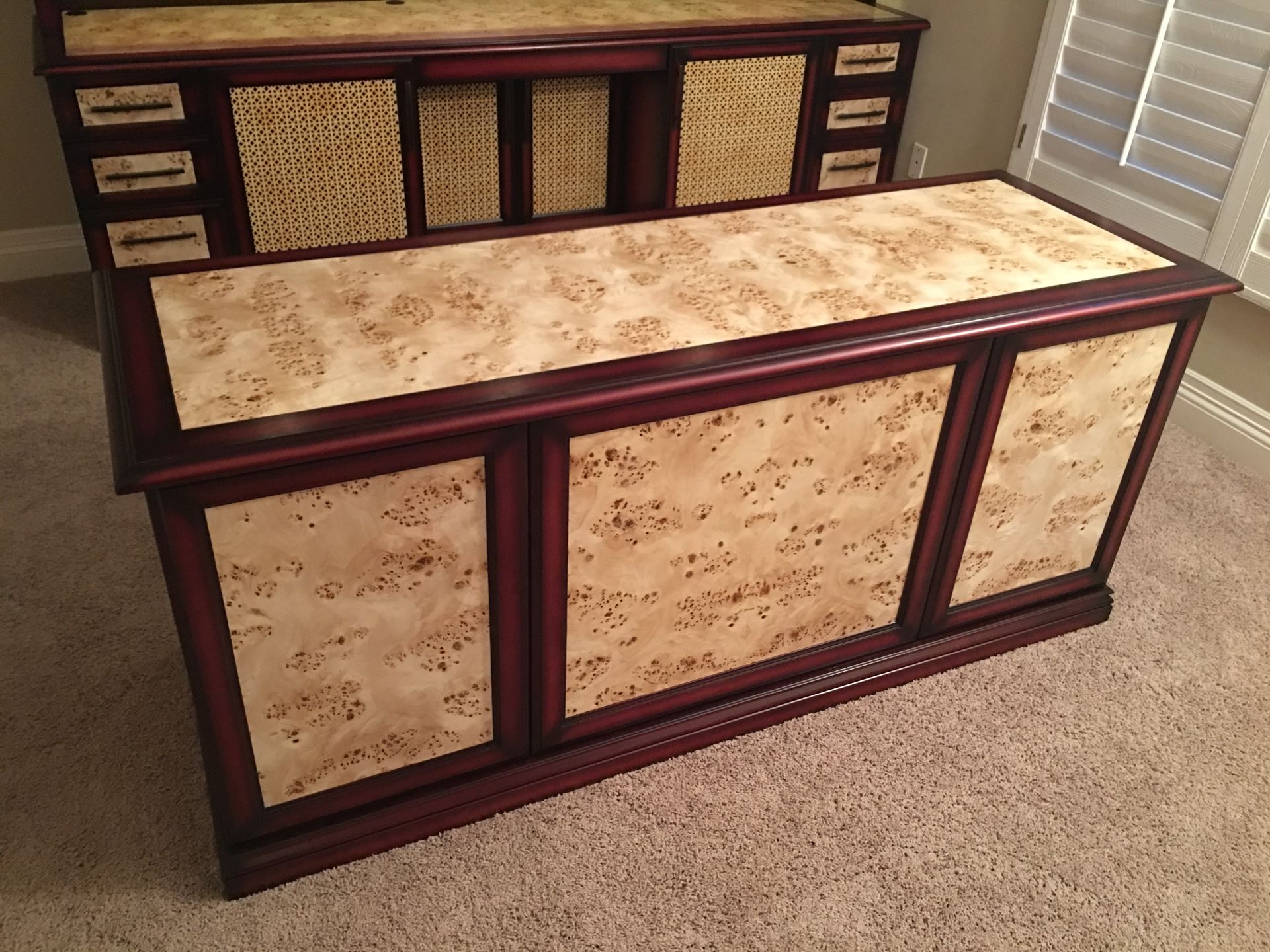Two wooden desks with light speckled panels and dark trim, on beige carpet.