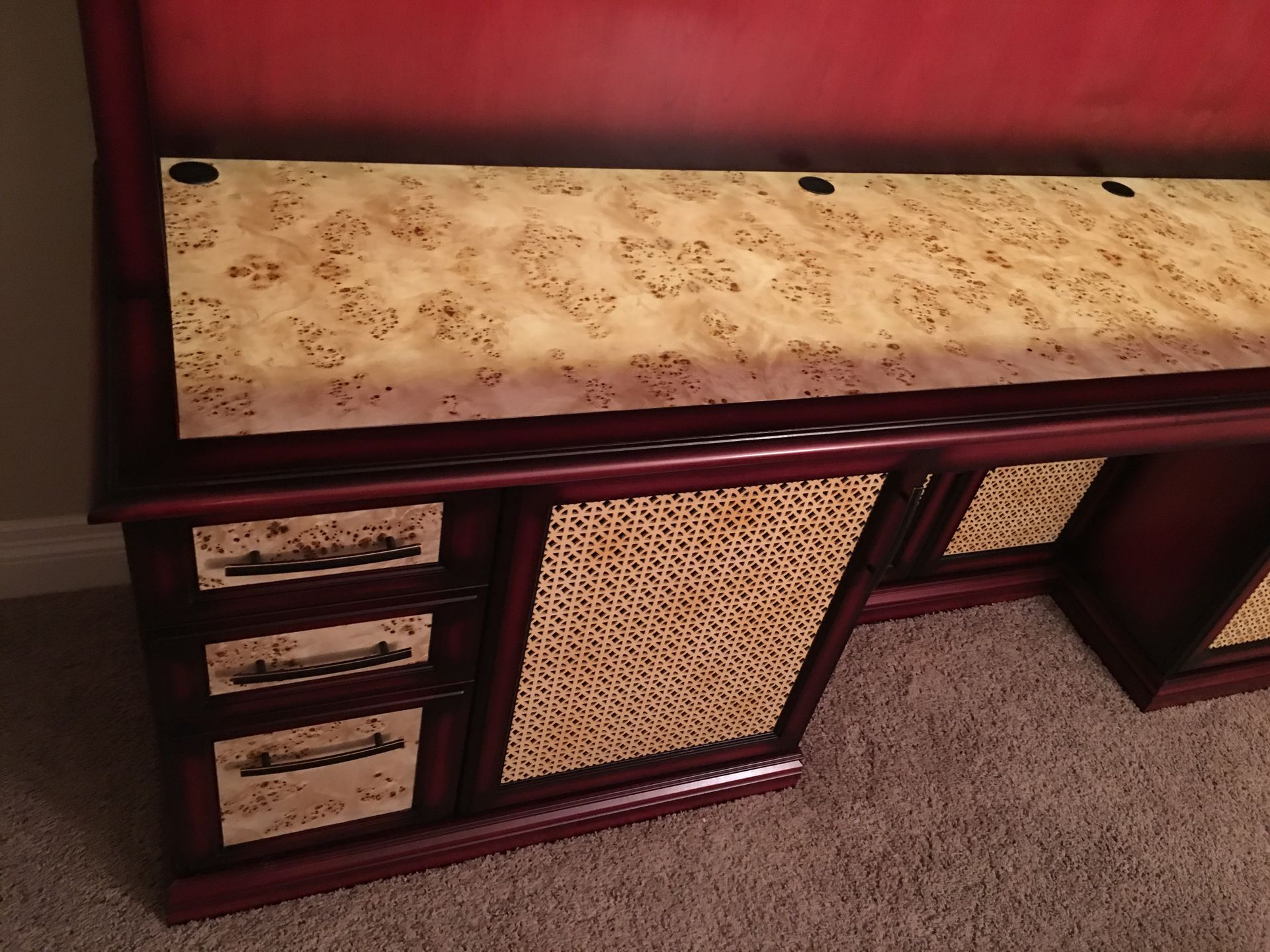 Dark wooden desk with three drawers, textured panel, and light-colored top.