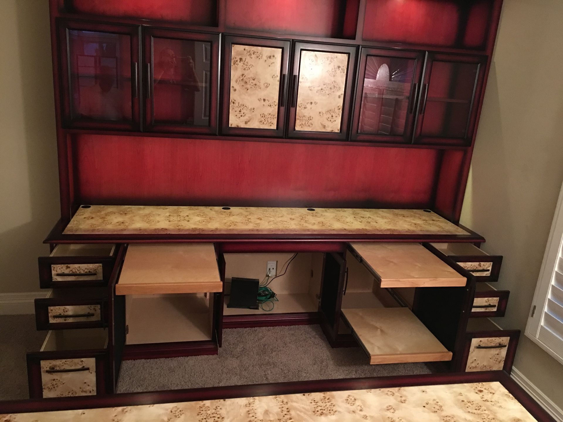Red and beige built-in desk with upper storage cabinets and pull-out keyboard shelves.