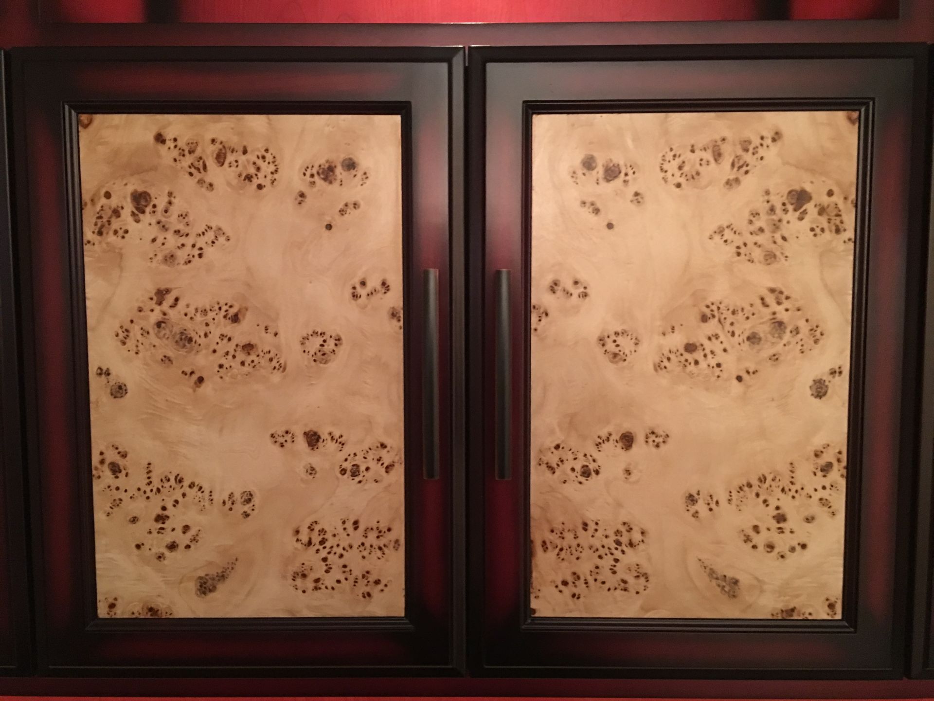 Two dark wood cabinet doors with light wood burled inserts and dark handles.