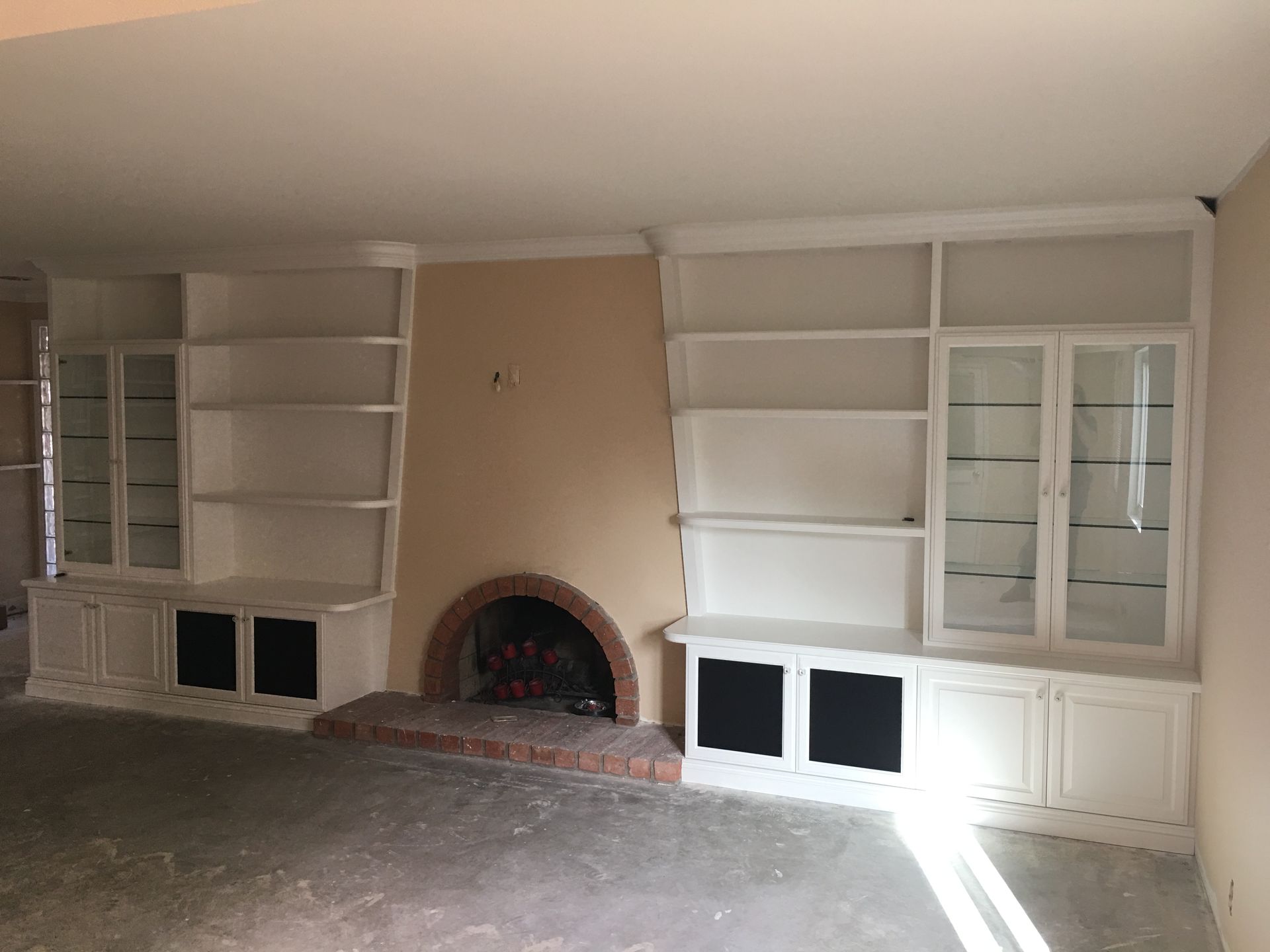 Built-in white bookshelves flanking a fireplace, with cabinets and glass-front display.