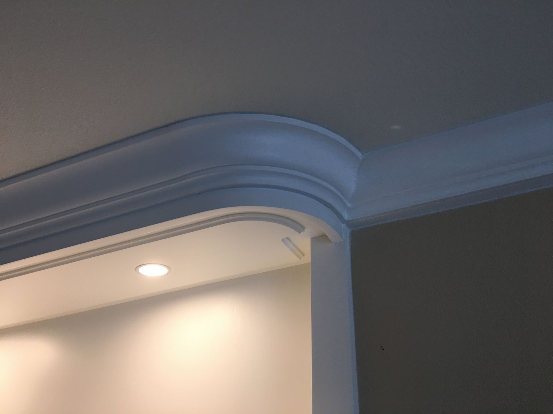 White curved crown molding on a wall corner, above a built-in recessed light.
