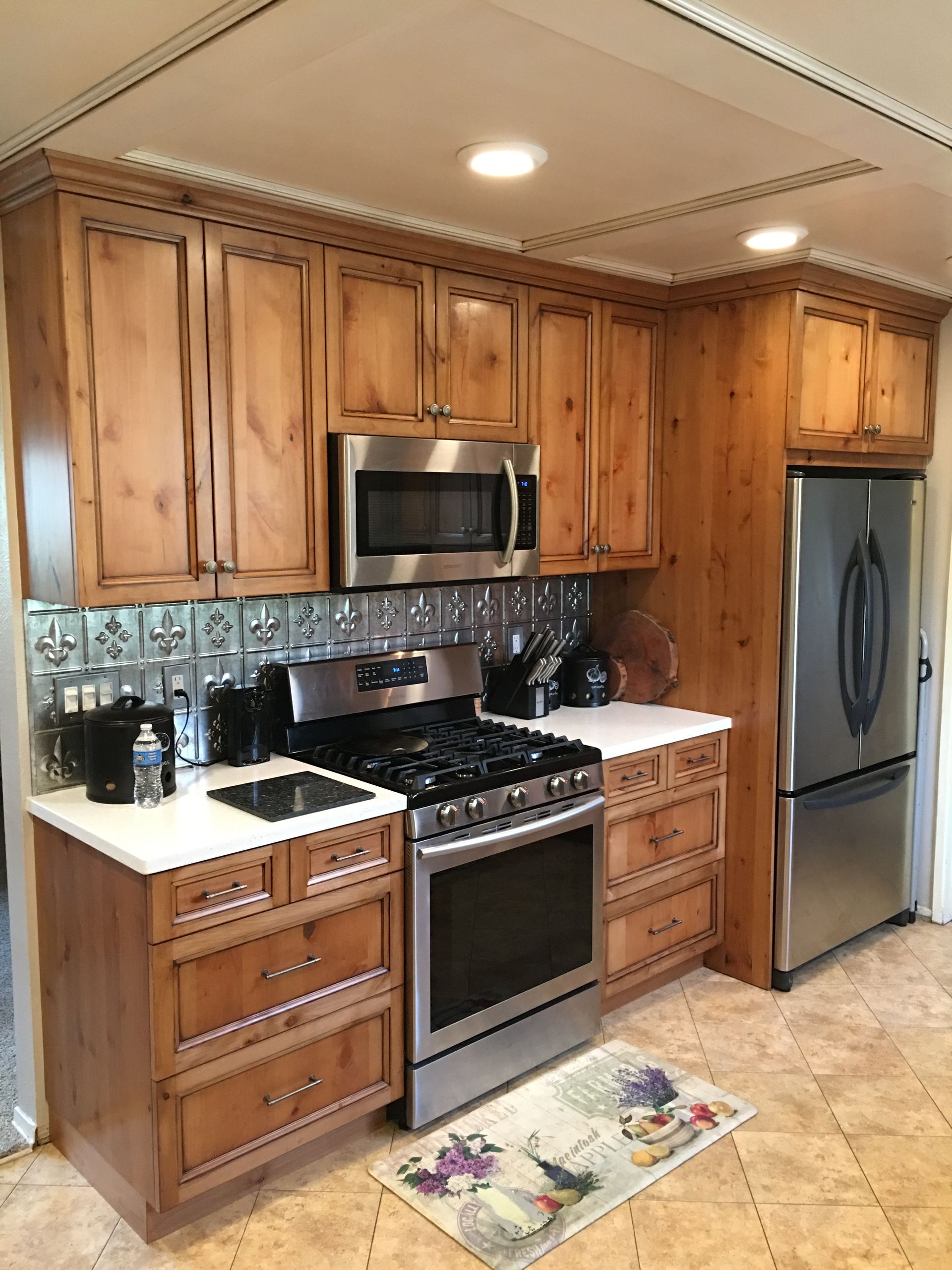 Kitchen with light-brown cabinets, stainless steel appliances, white countertops, and a decorative tile backsplash.