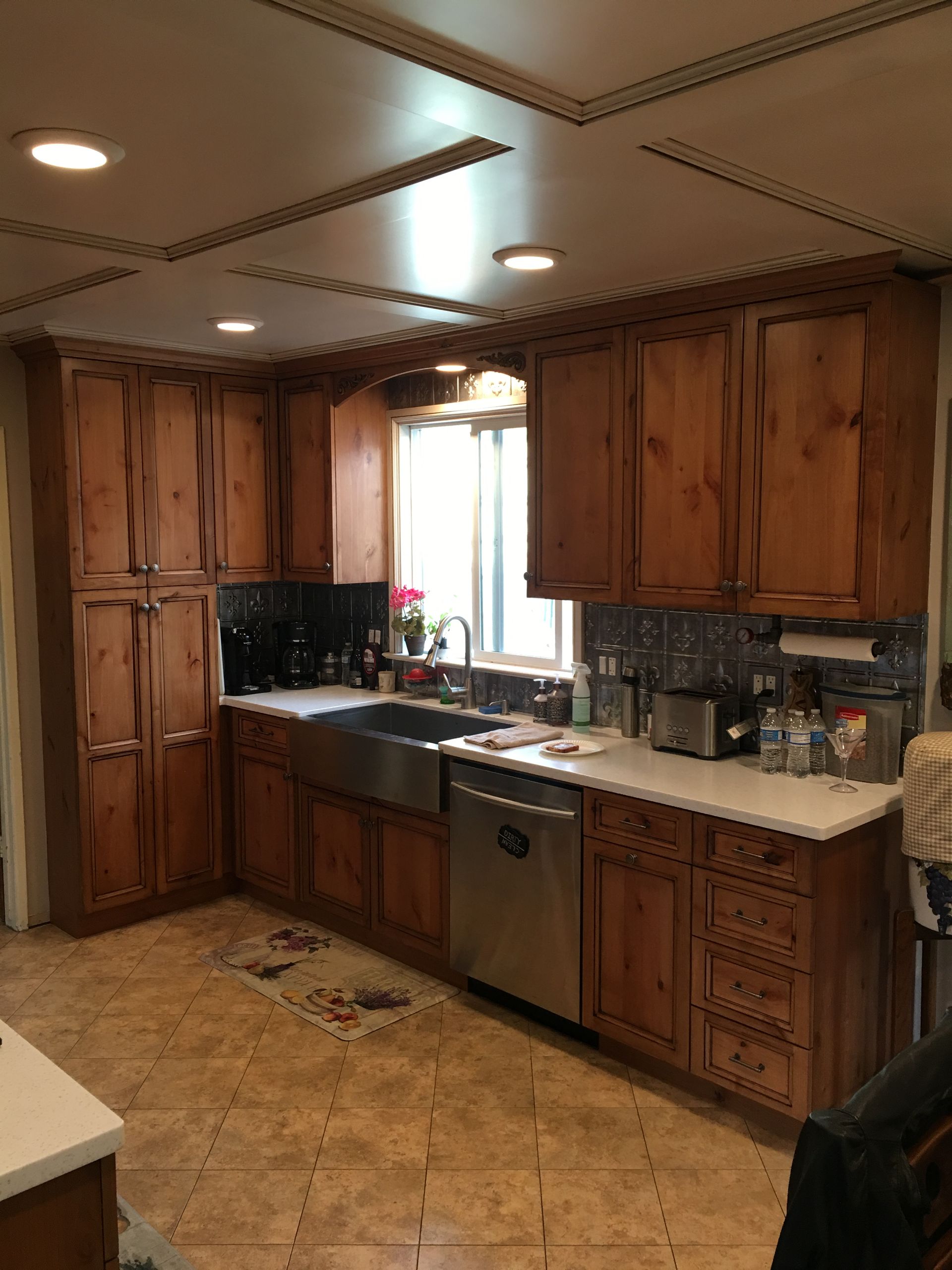 Kitchen with wood cabinets, stainless steel appliances, white countertops, and tile floor.
