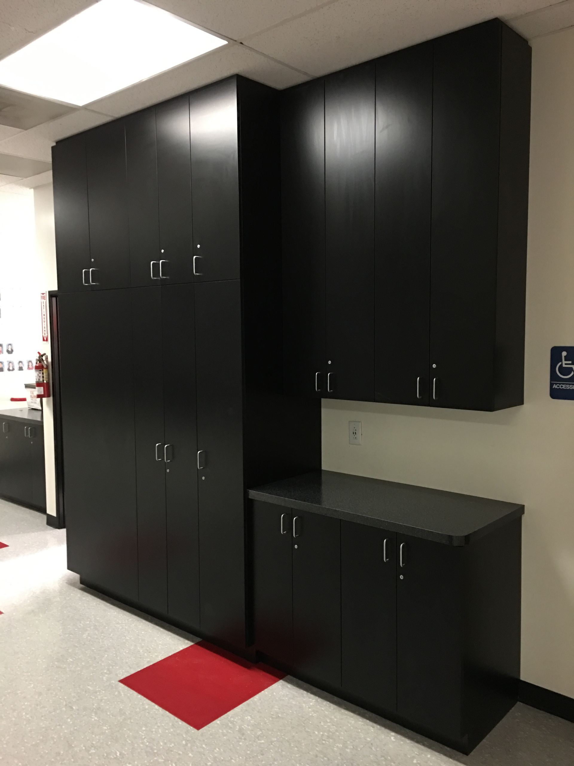 Black storage cabinets in an office. Cabinets are of various sizes and mounted on a wall.