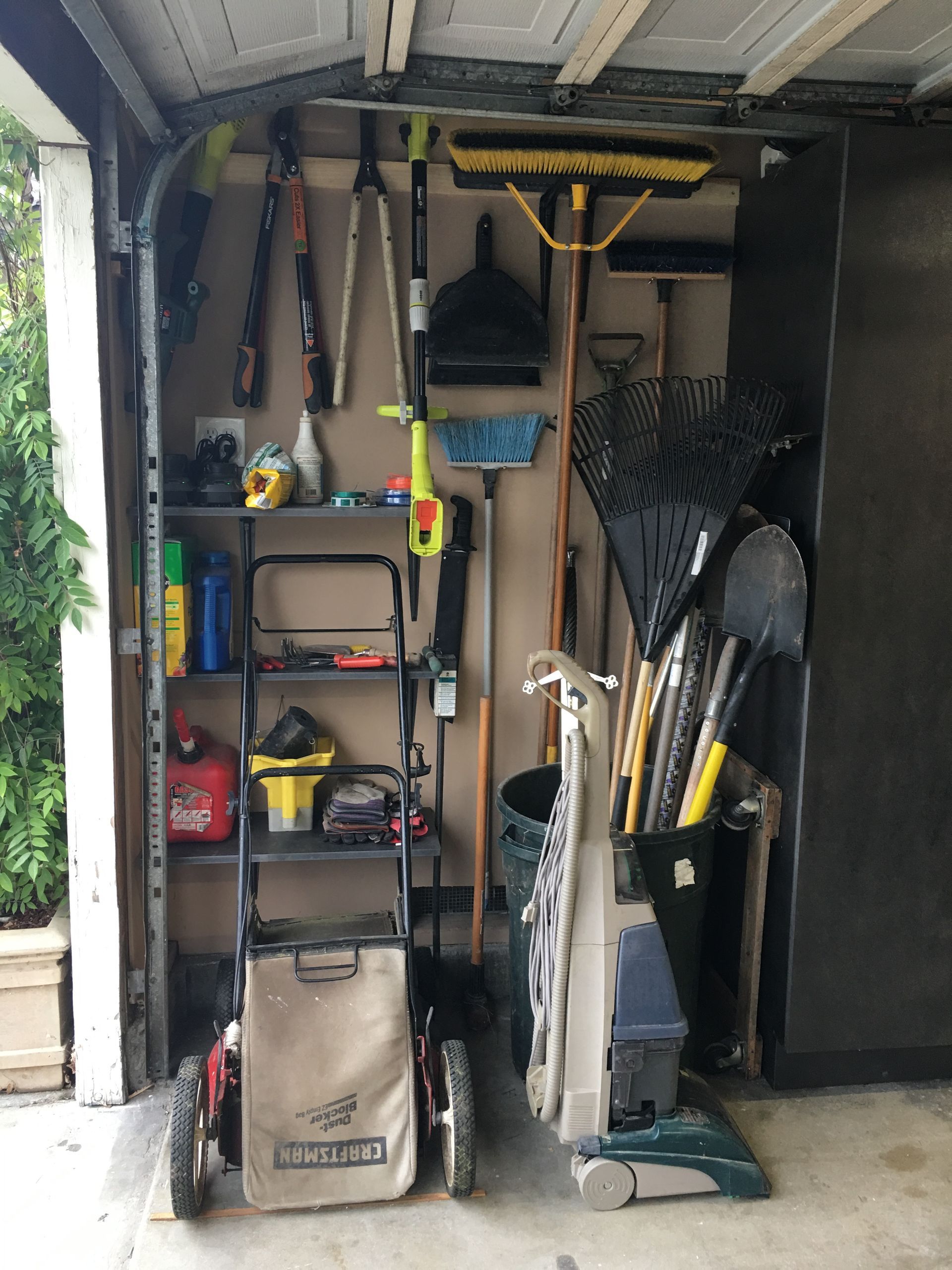 Garage tools: lawnmower, broom, rake, and other tools organized on wall shelves.