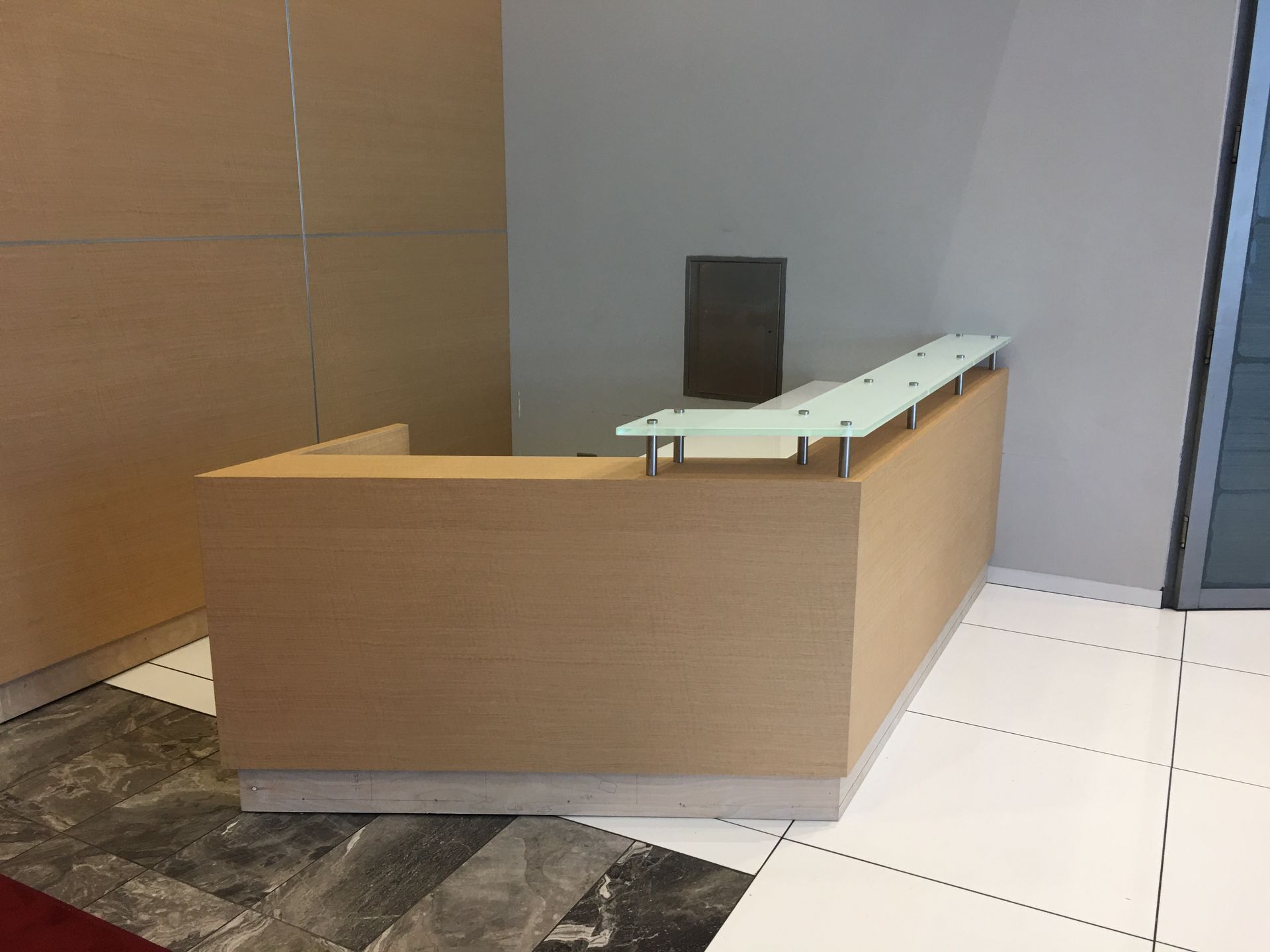 Beige wooden reception desk with a glass counter.