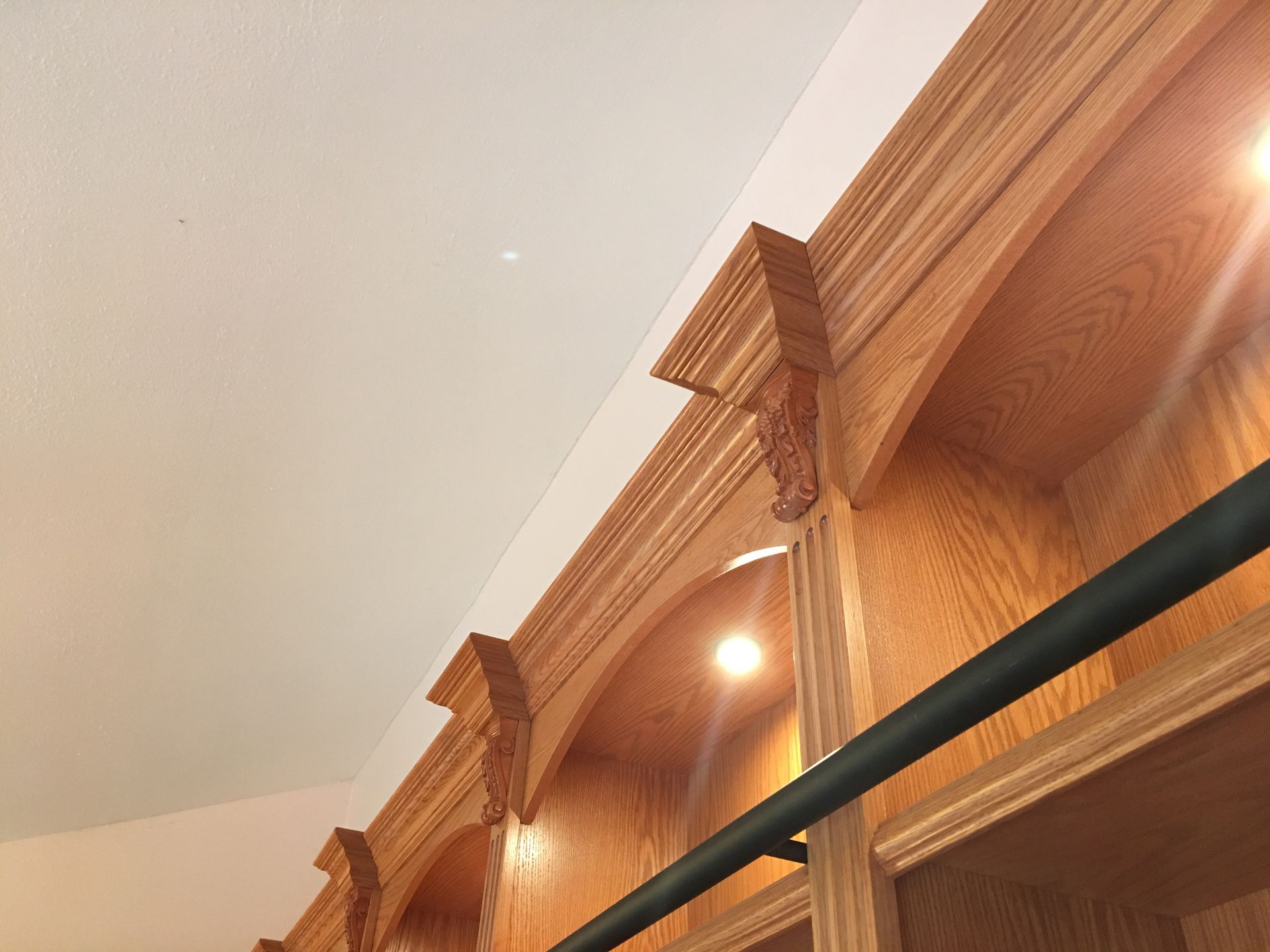 Wooden bookshelves with arched openings and decorative accents. Ceiling visible above.