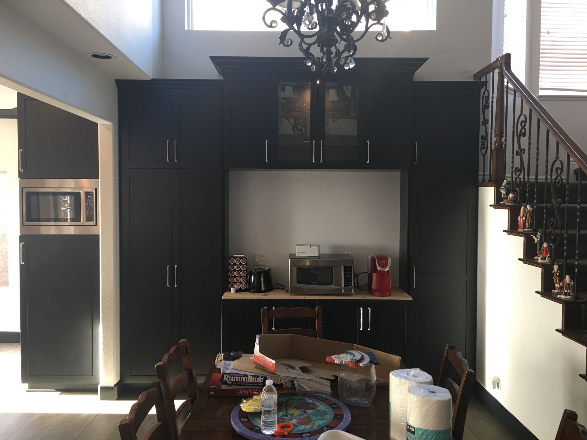 Black cabinets with appliances and dining table in a room with a staircase.