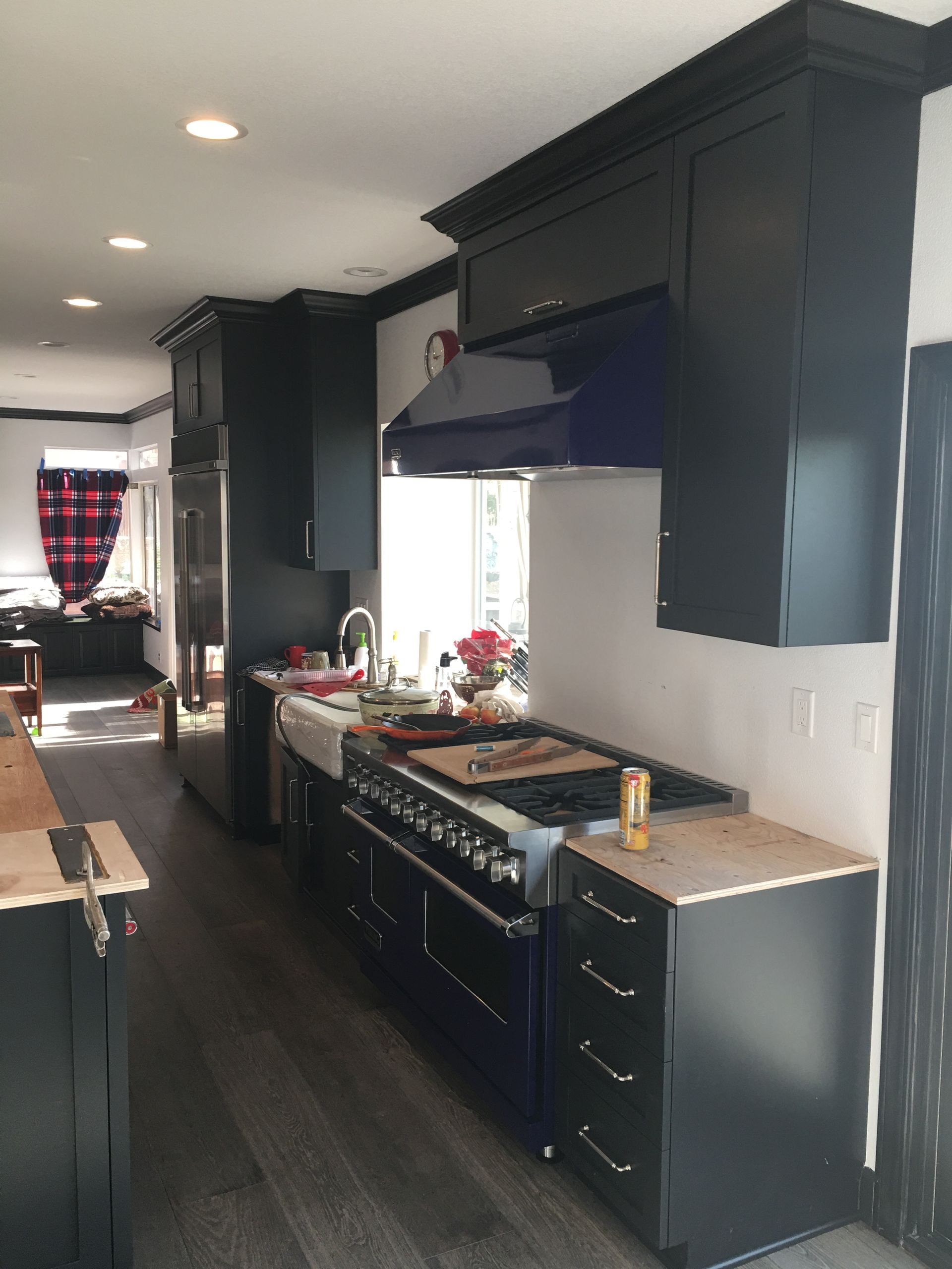 Dark blue kitchen with a stainless steel refrigerator, white walls, and a blue range.