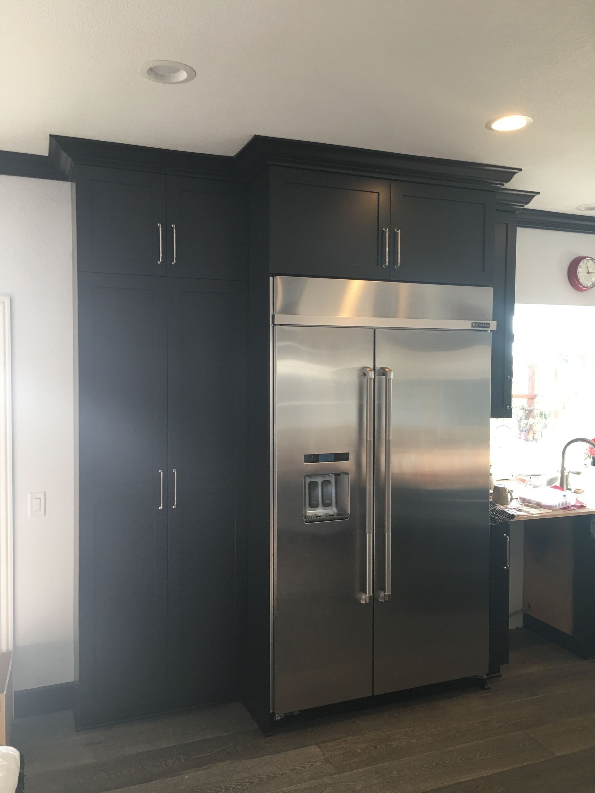 Stainless steel refrigerator next to dark cabinets in a kitchen.