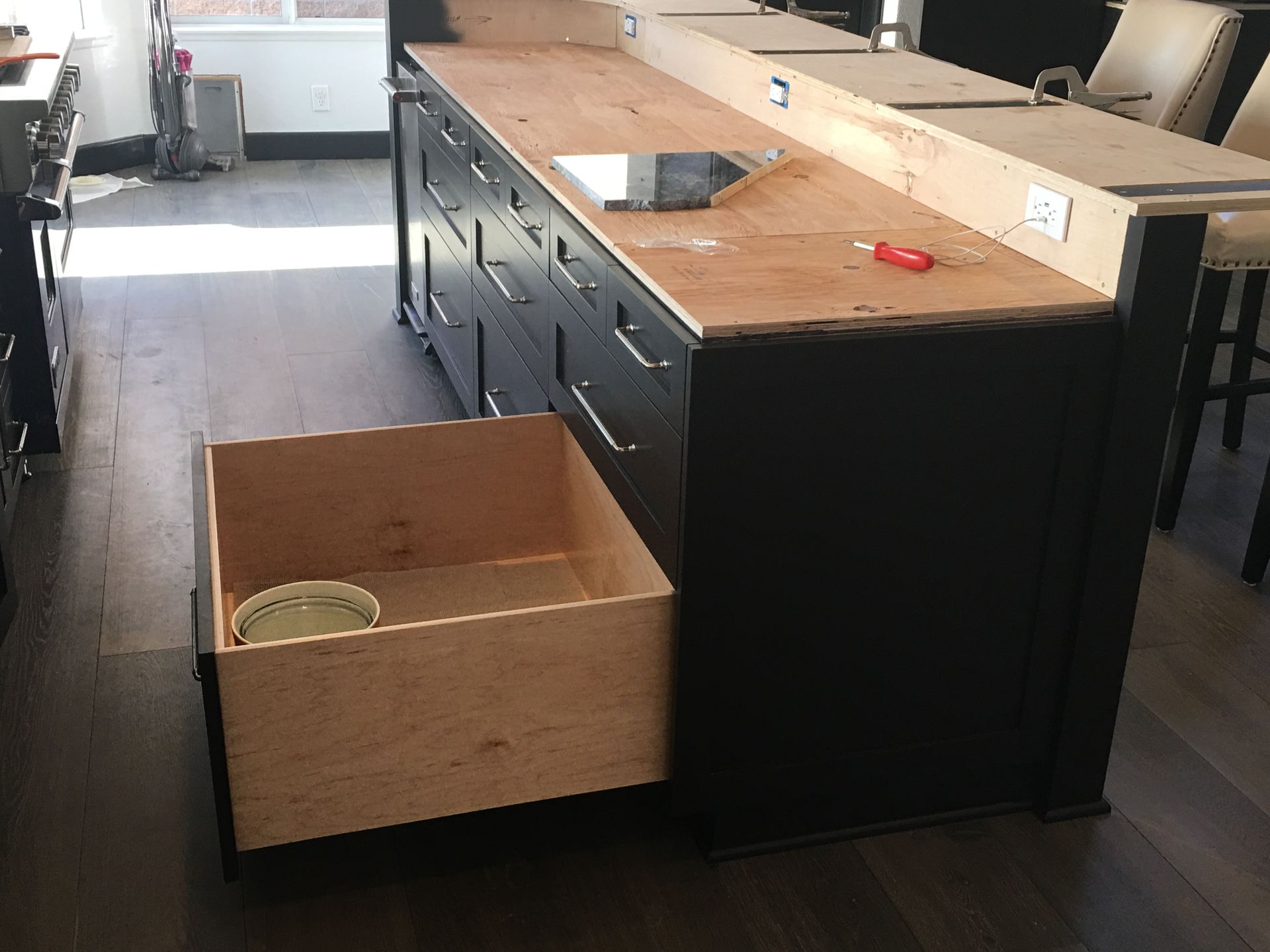 Black kitchen island with unfinished wood countertop and open drawer.