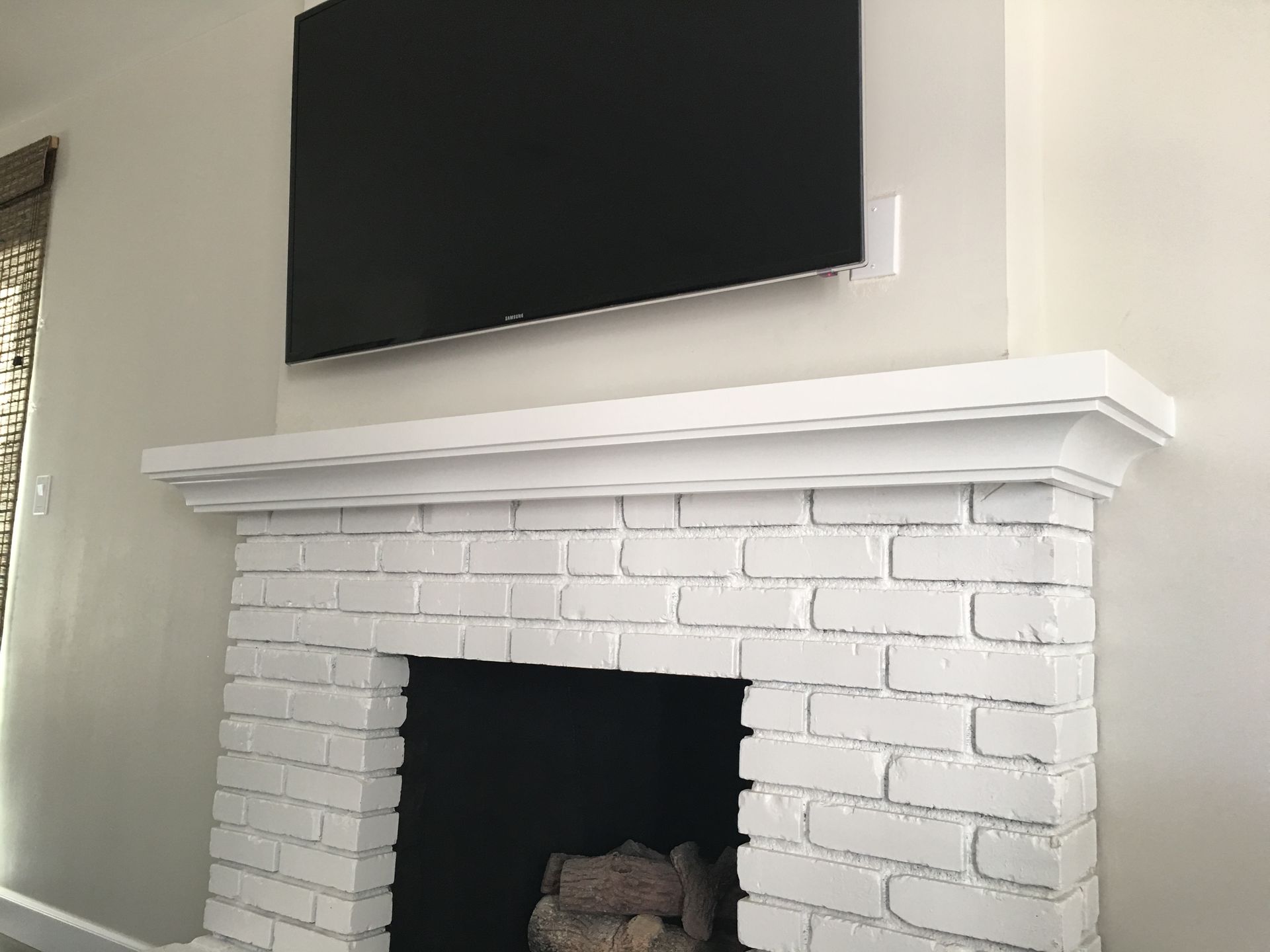 White brick fireplace with white mantle; a black TV is mounted above.