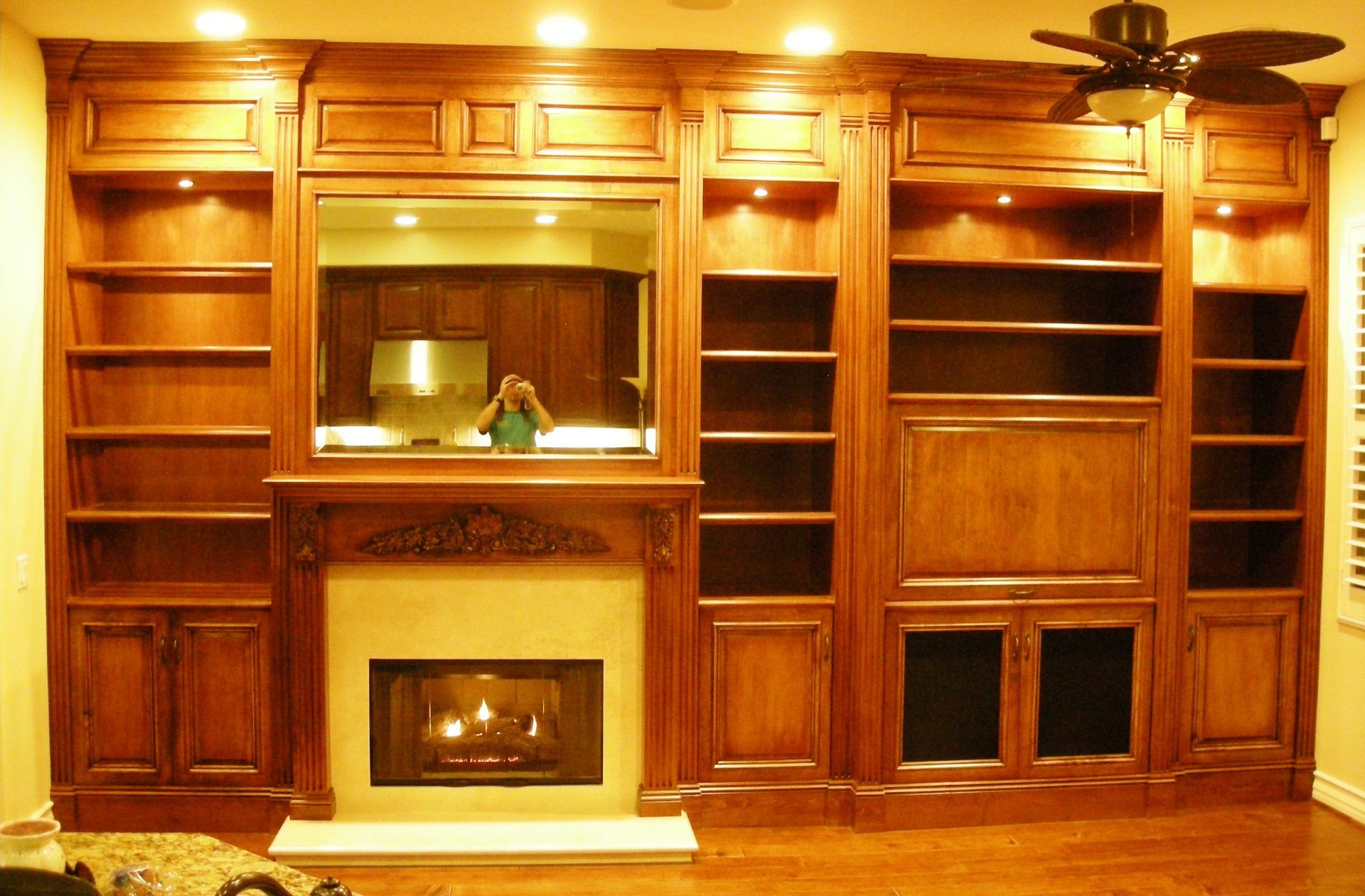 Built-in wooden entertainment center with fireplace, bookshelves, and cabinet storage. Interior of a home.