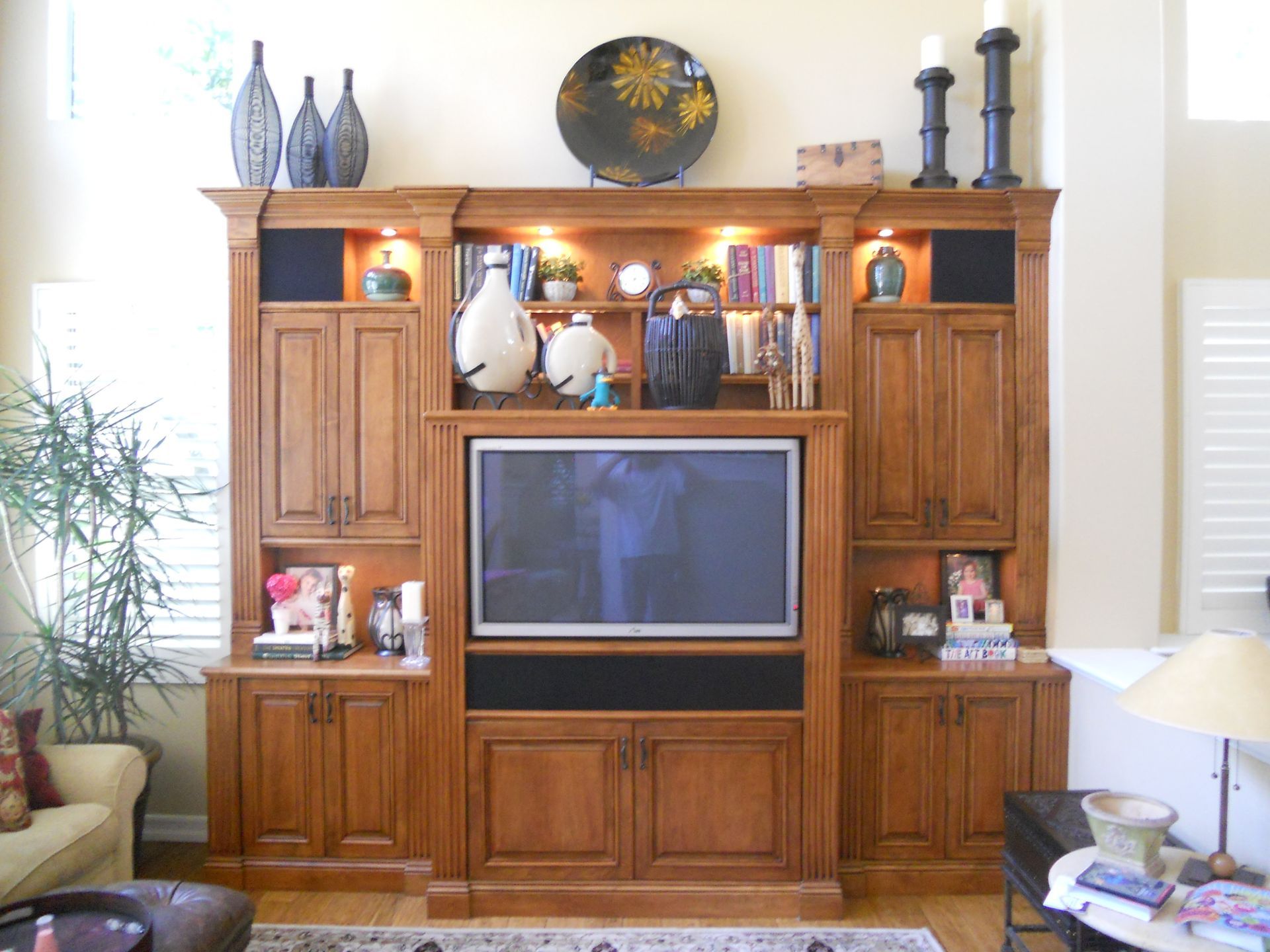 Wooden media center with TV, storage cabinets, and decorative items.