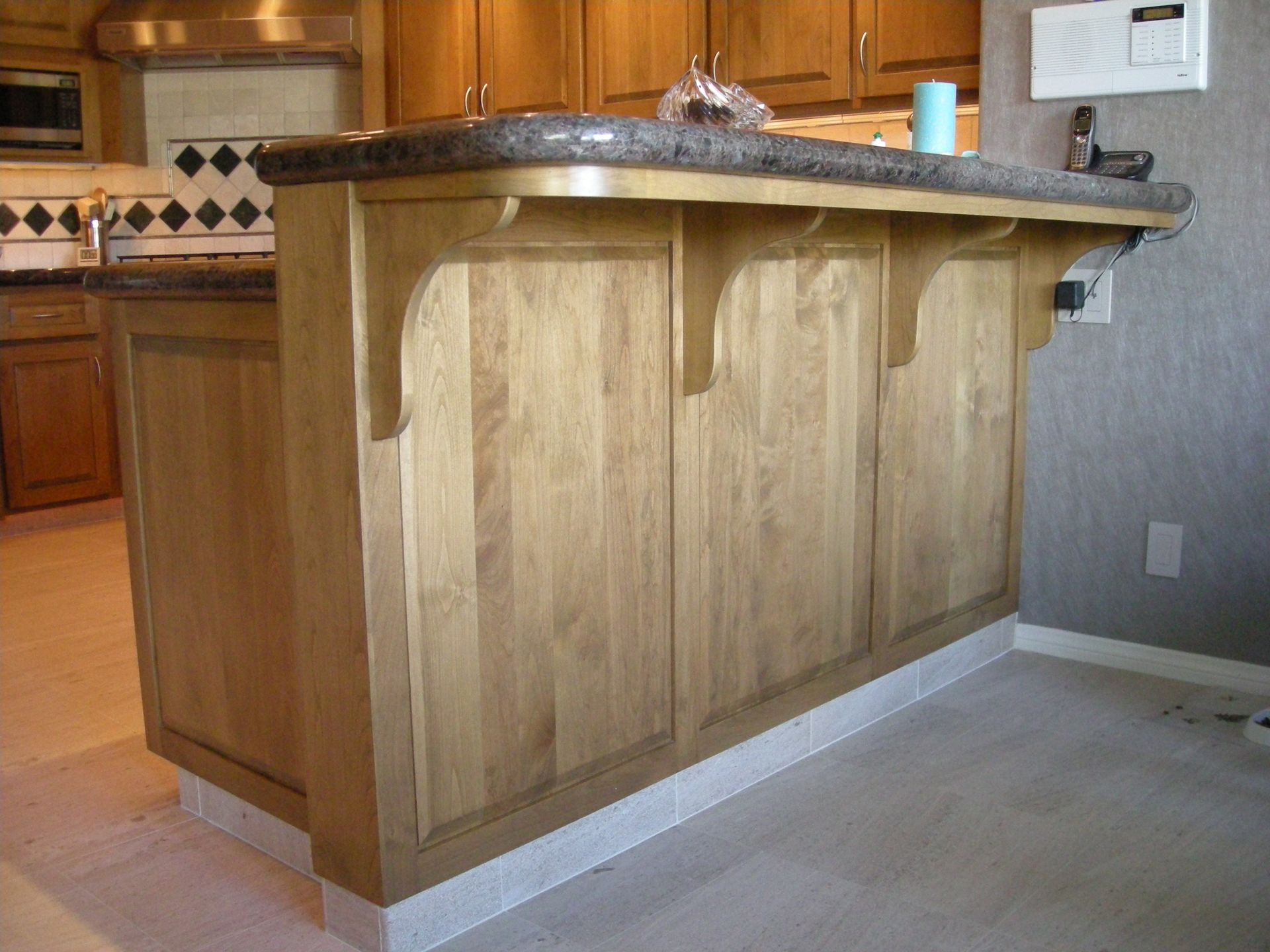 Wooden kitchen island with a granite countertop and decorative supports.