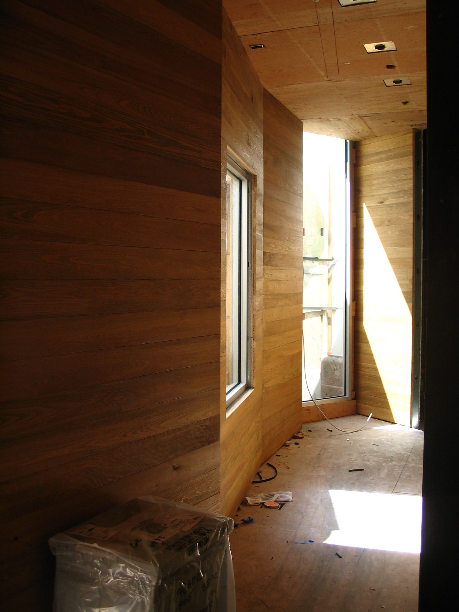 Interior hallway with earth-toned walls. A window at the end lets in bright light.
