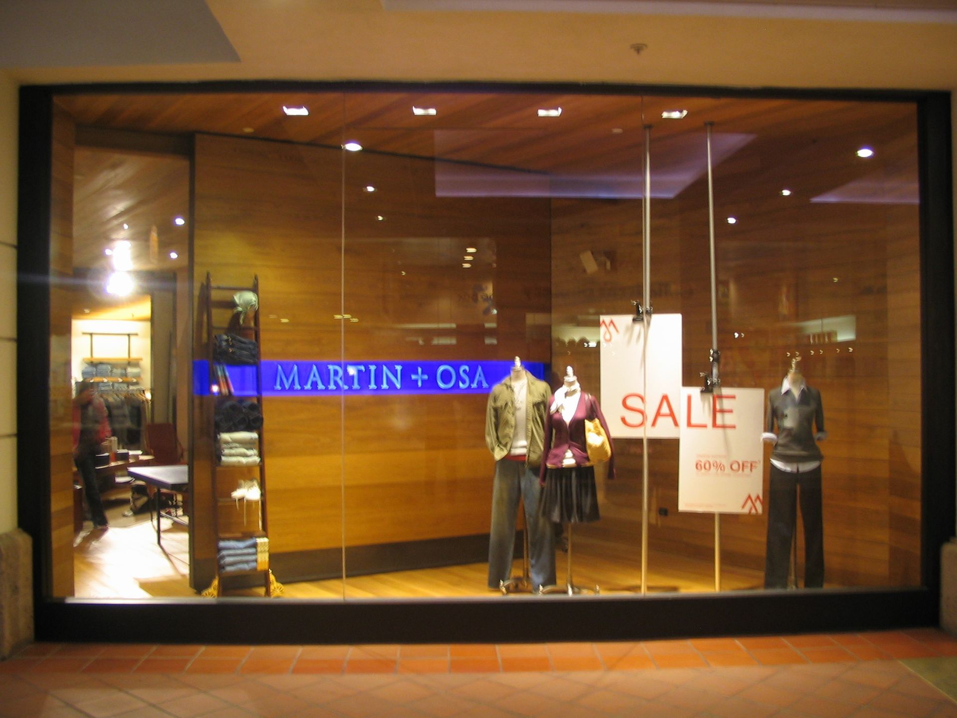Storefront window display with mannequins wearing clothing and a 