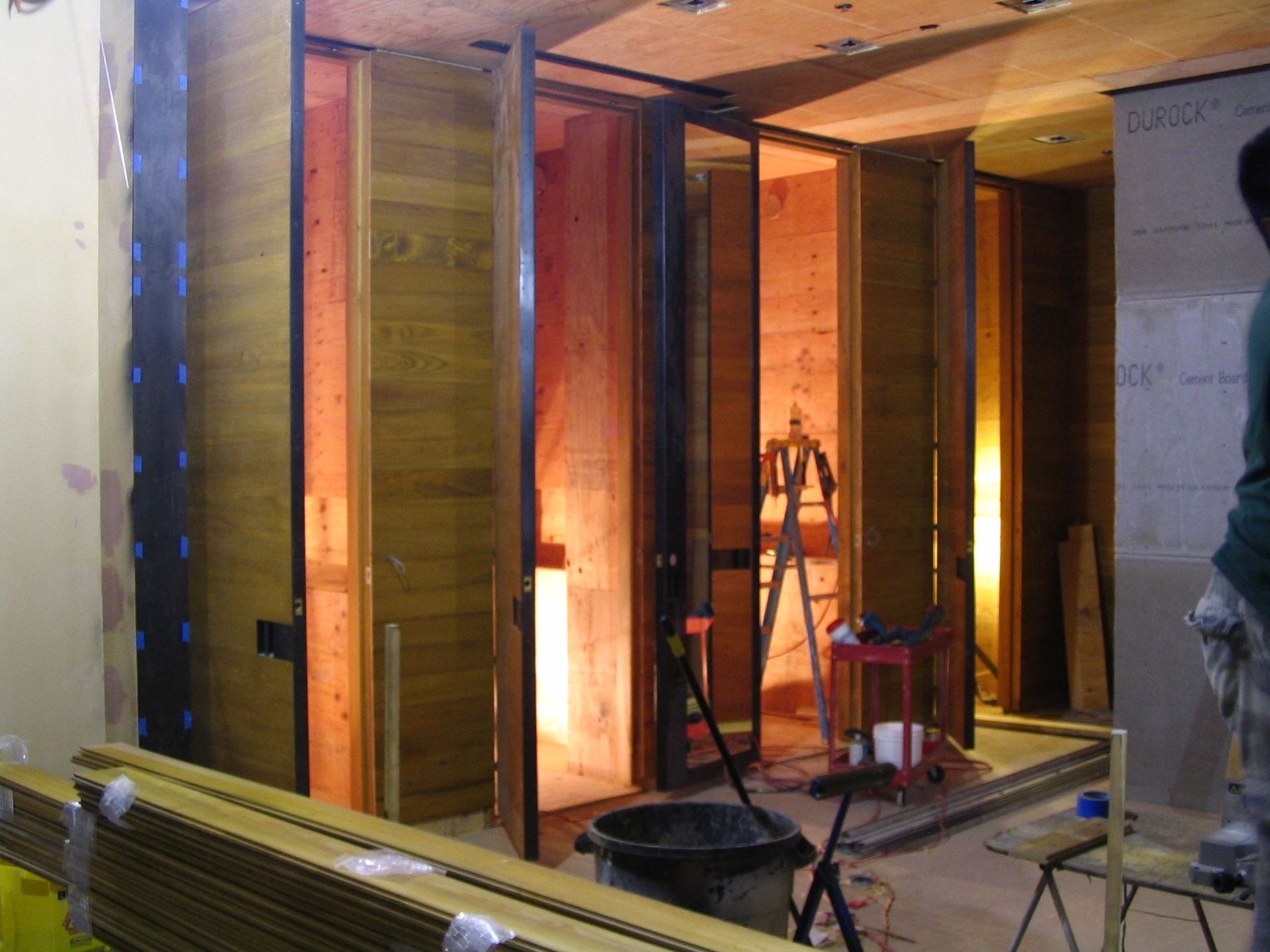 Interior construction site with wooden doors, a ladder, and tools.