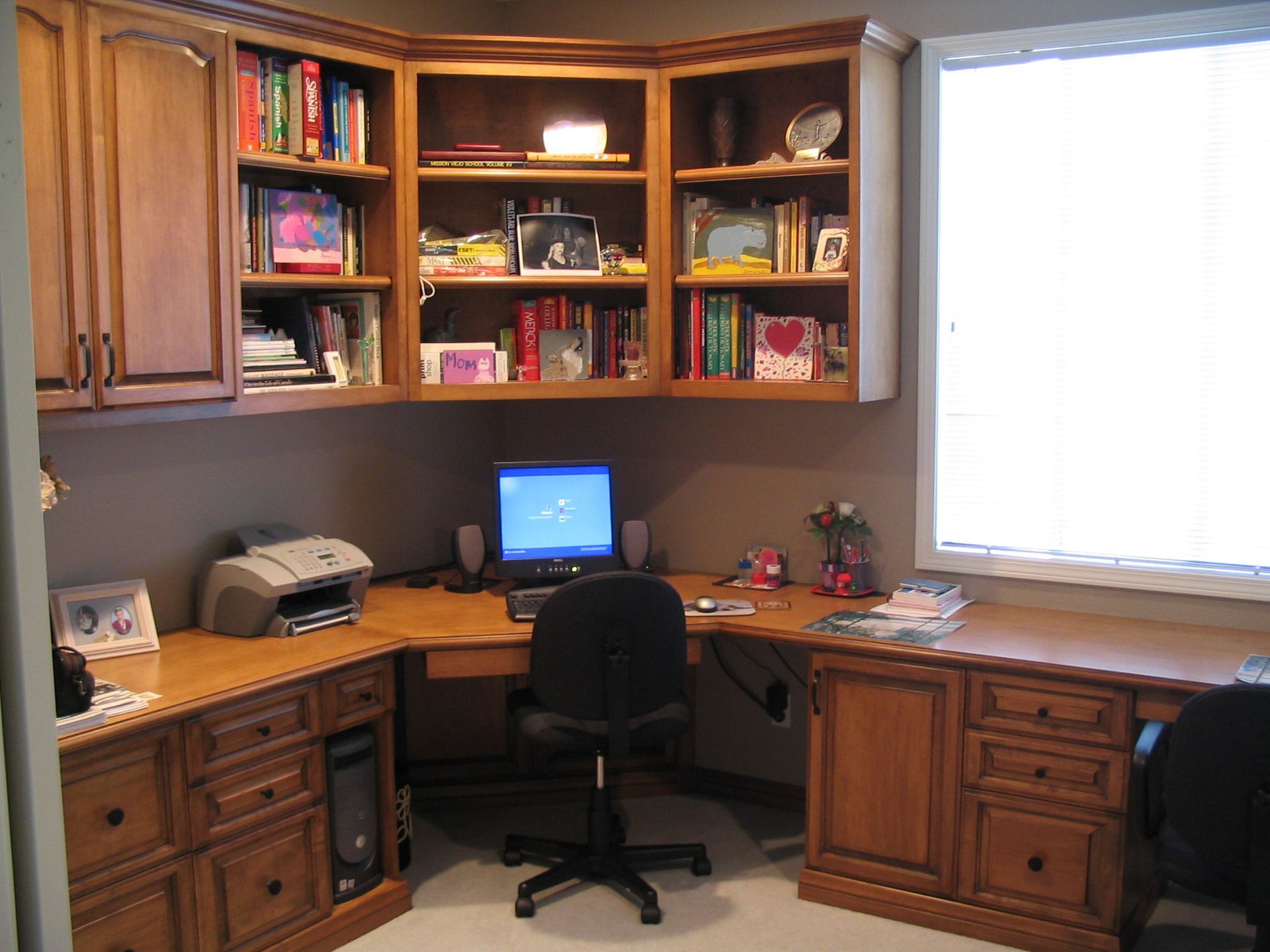 Corner home office with wood cabinets, desk, computer, and books.