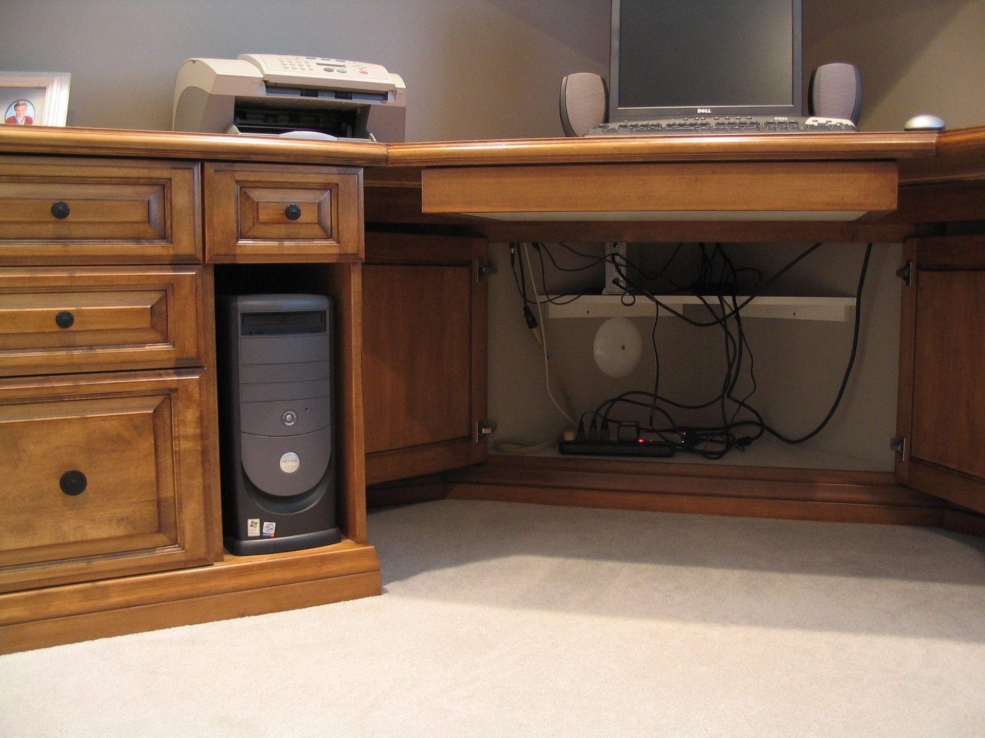 Computer desk with printer, monitor, speakers, and computer tower.