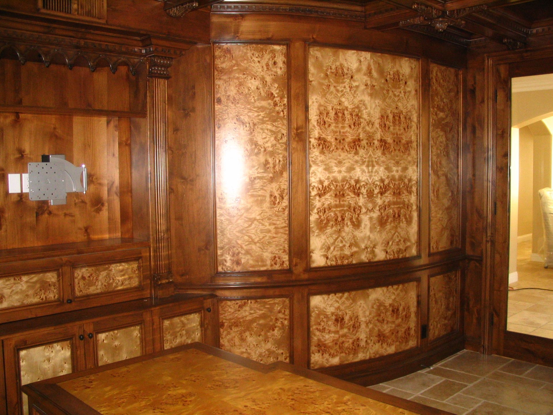 Wooden paneled room with ornate trim, featuring a desk and wall panels with burl wood detailing.