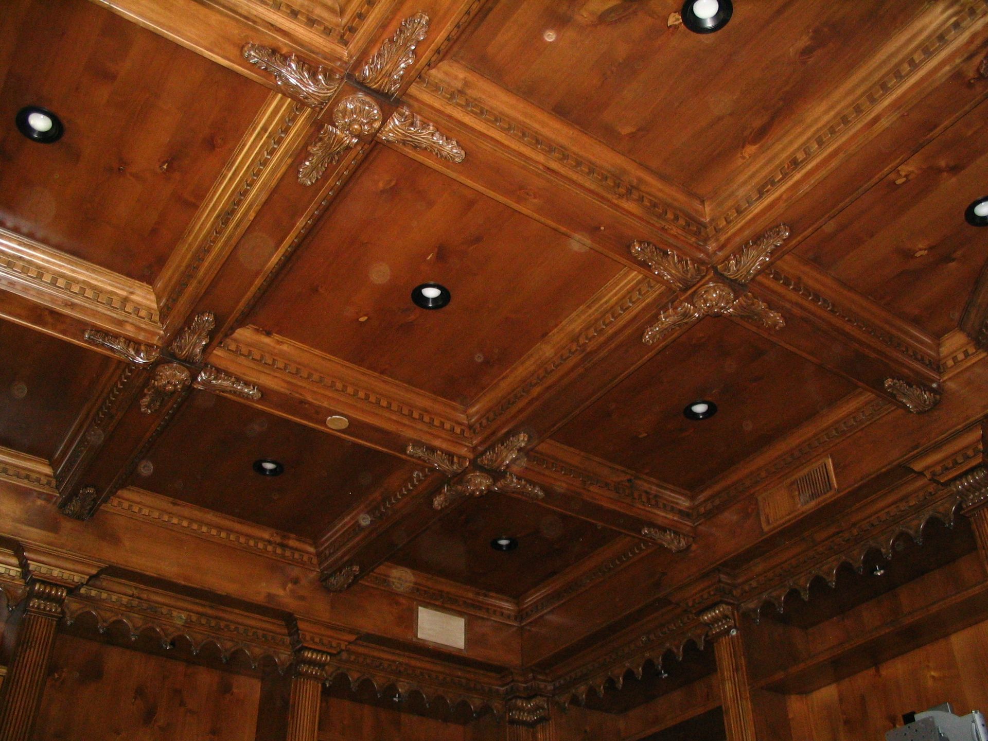 Ornate wooden ceiling with recessed lighting and decorative molding.