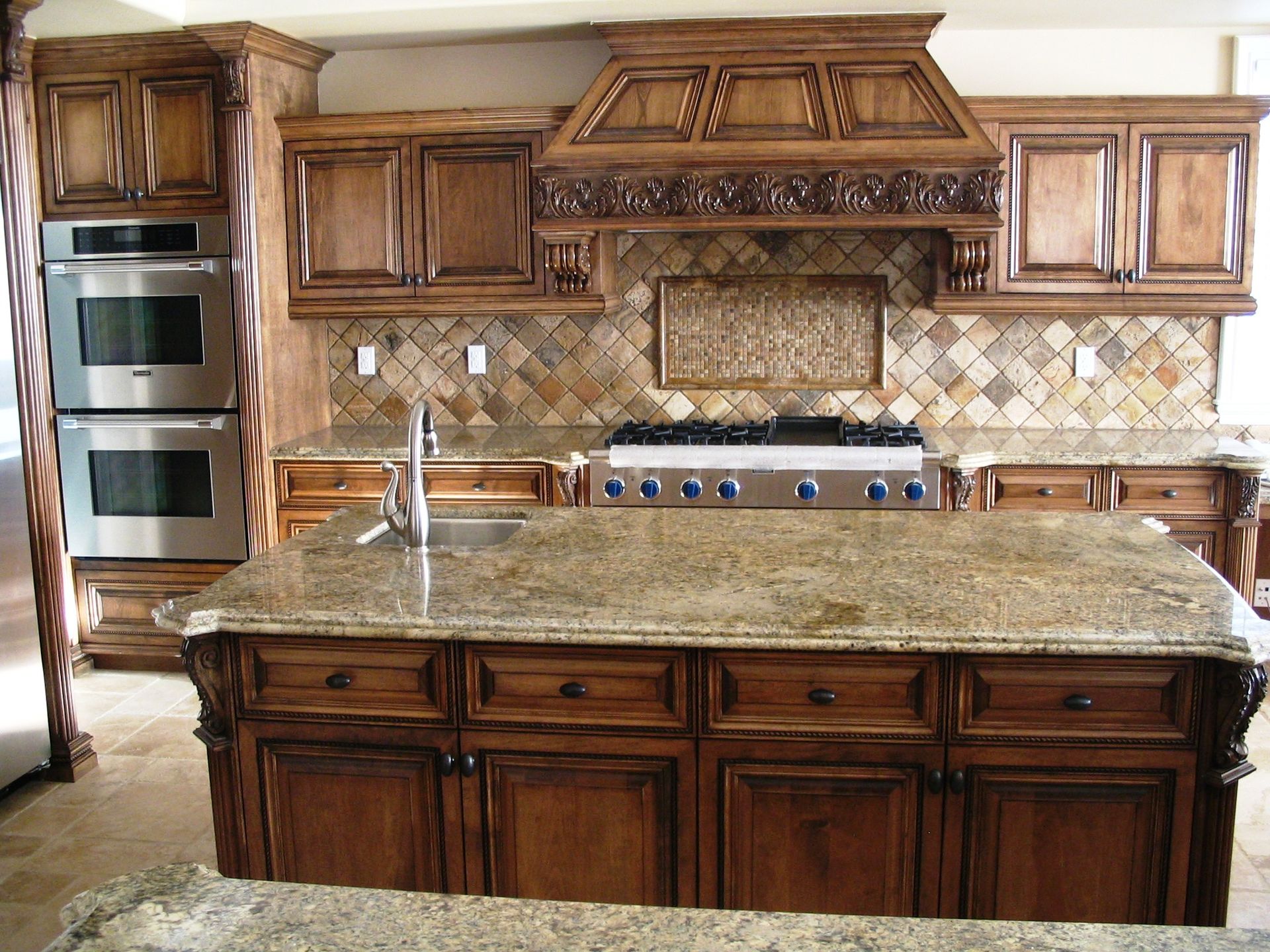 Luxurious brown kitchen with a large island and stainless steel appliances.
