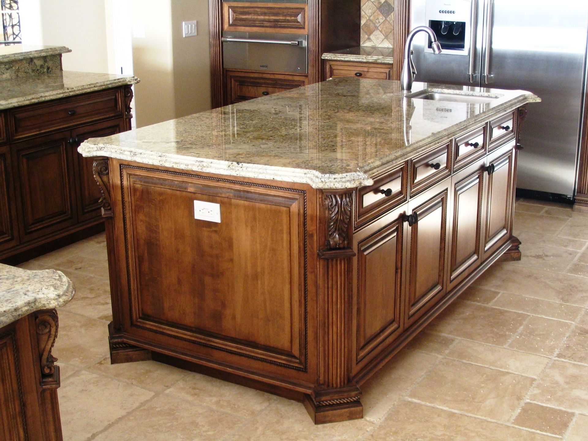Kitchen island with granite countertop and wood cabinetry. Sink and faucet visible.