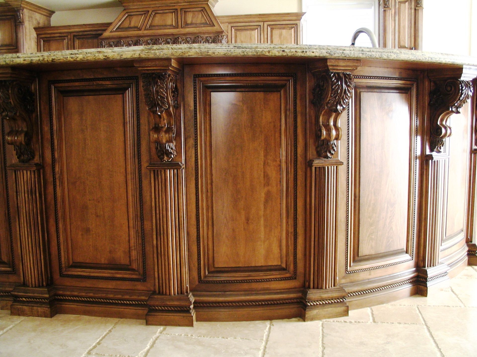 Wooden kitchen island with ornate carvings and a granite countertop.