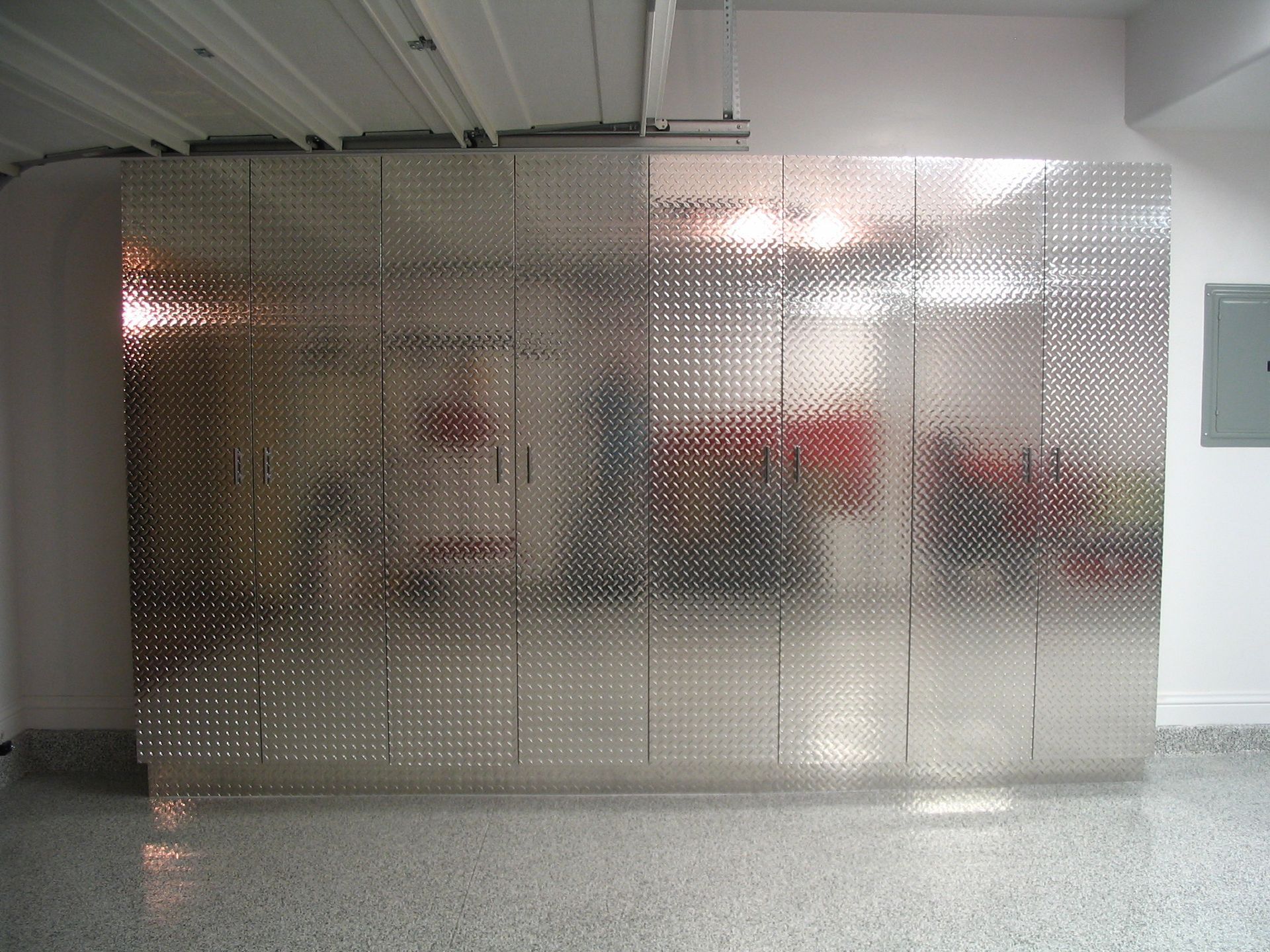 Silver perforated metal wall in a garage, reflecting the surroundings.