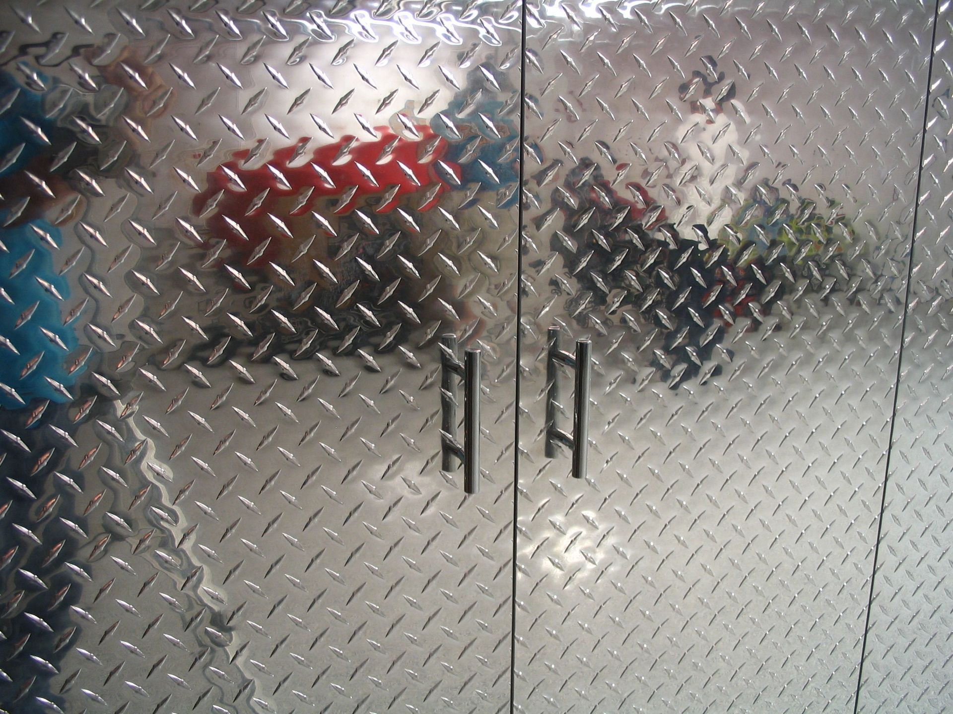 Metal cabinet with diamond plate pattern and black handles.