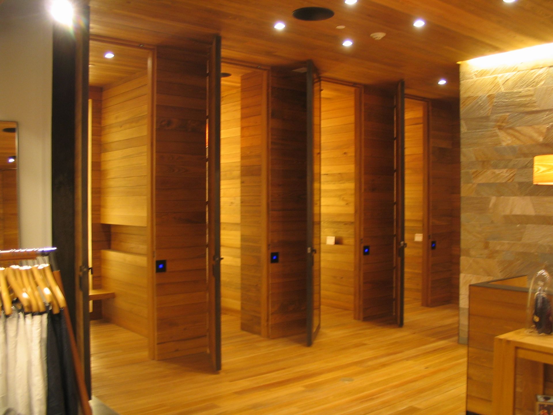 Wooden changing rooms, open doors, warm wood tones, recessed lighting.
