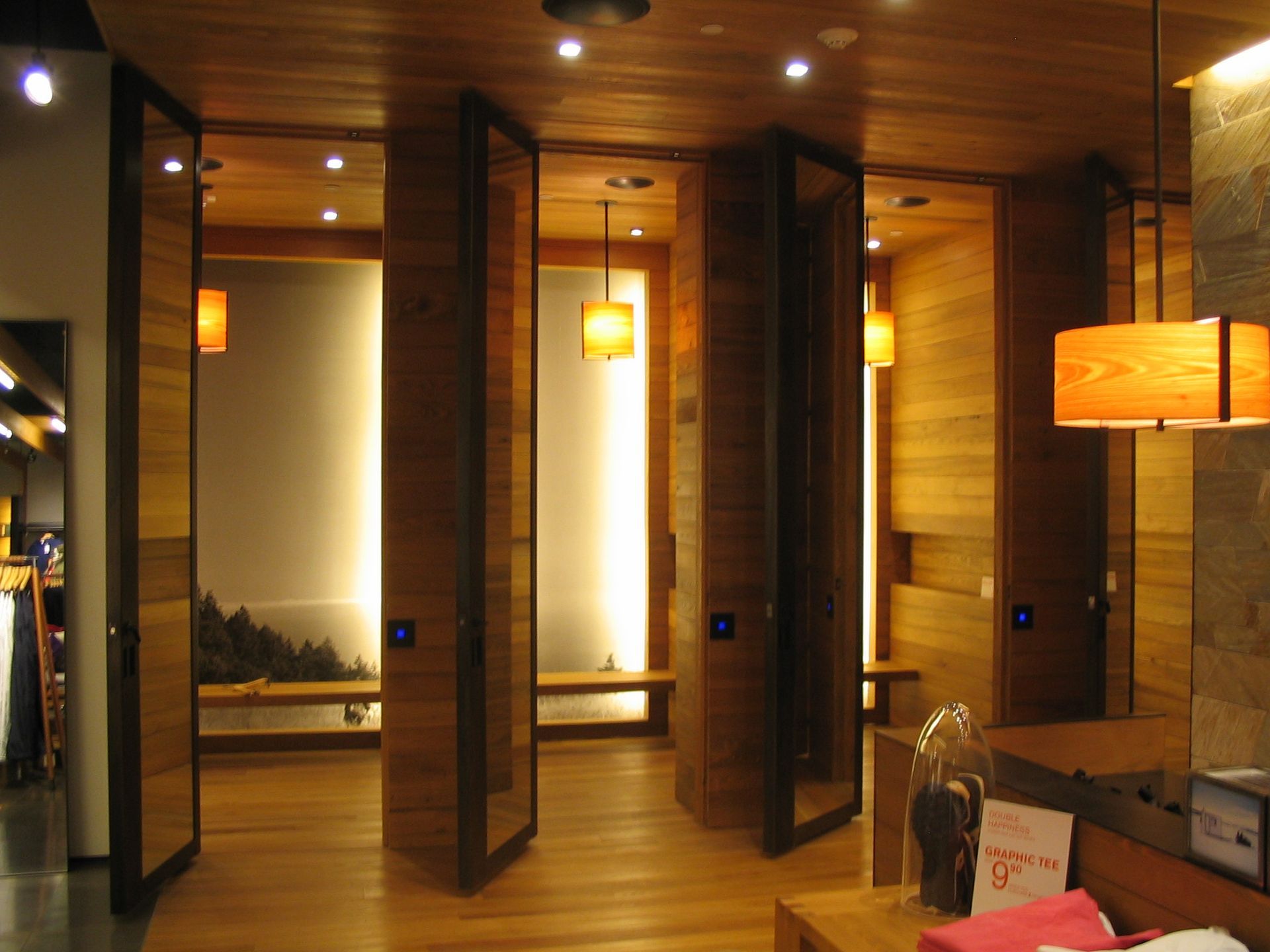 Wooden spa interior with several open changing rooms, each with a bench and soft lighting.