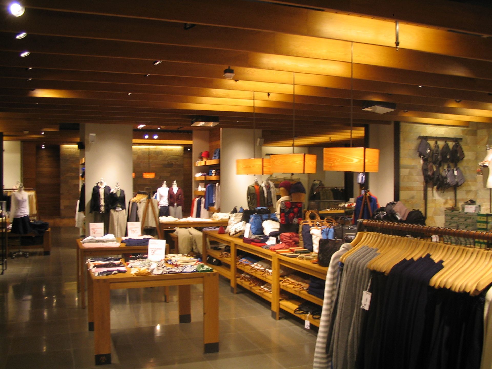 Clothing store interior with wooden accents, clothing racks, and display tables.