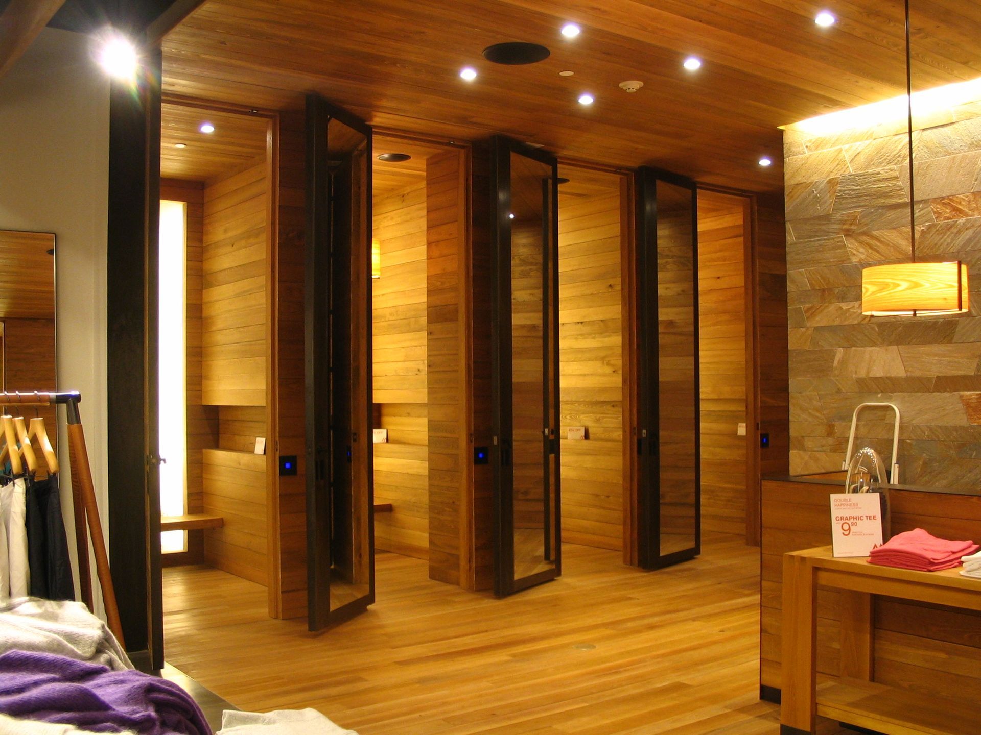 Clothing store with wood paneling, tall mirrors, and overhead lighting.