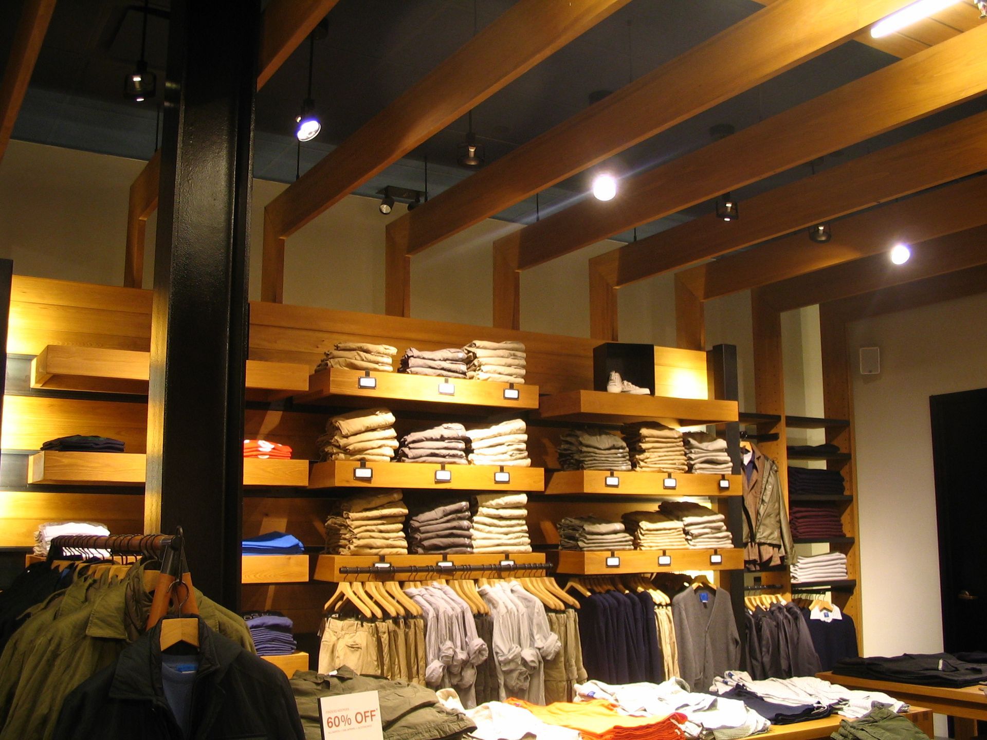 Clothing store interior with stacked clothes on wooden shelves and racks.