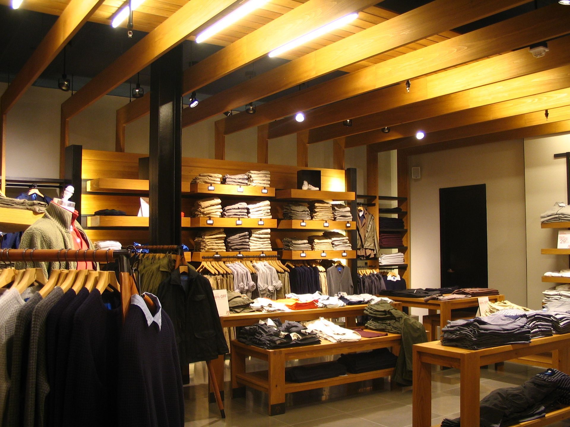 Clothing store interior with wooden shelving and clothing racks.