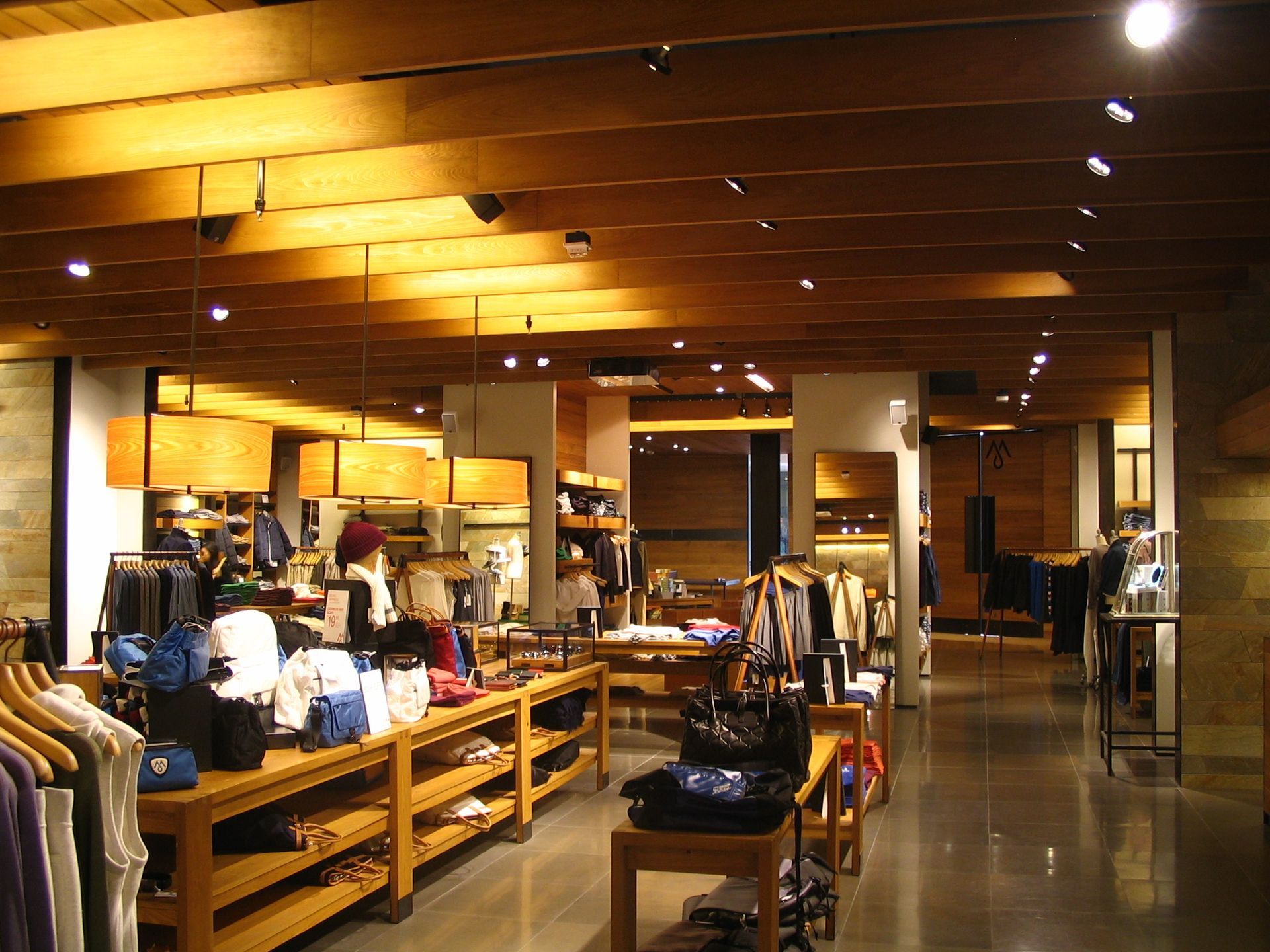 Clothing store interior with wooden beams, display tables, and merchandise.