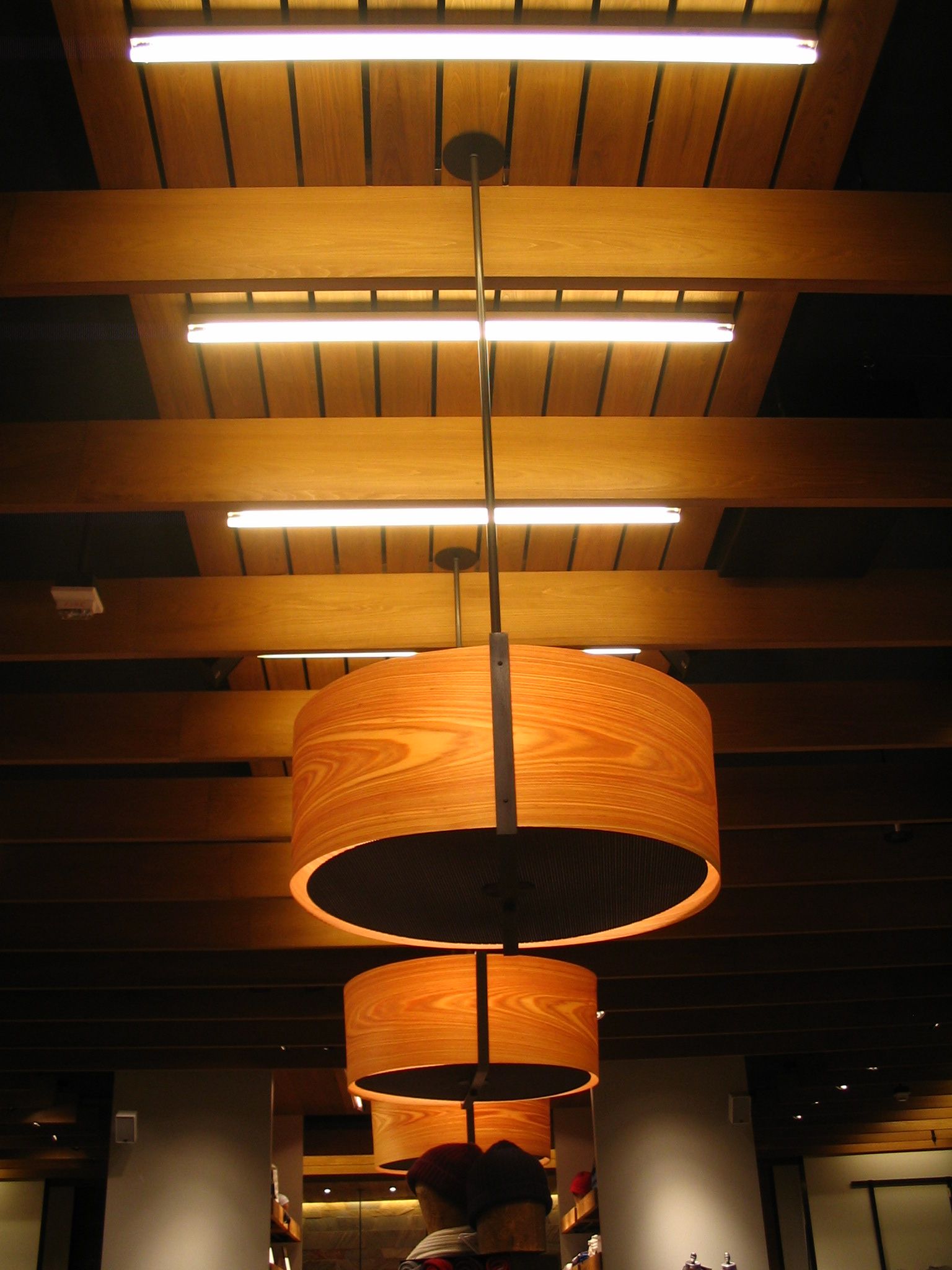 Wooden pendant lights hanging below fluorescent ceiling lights.