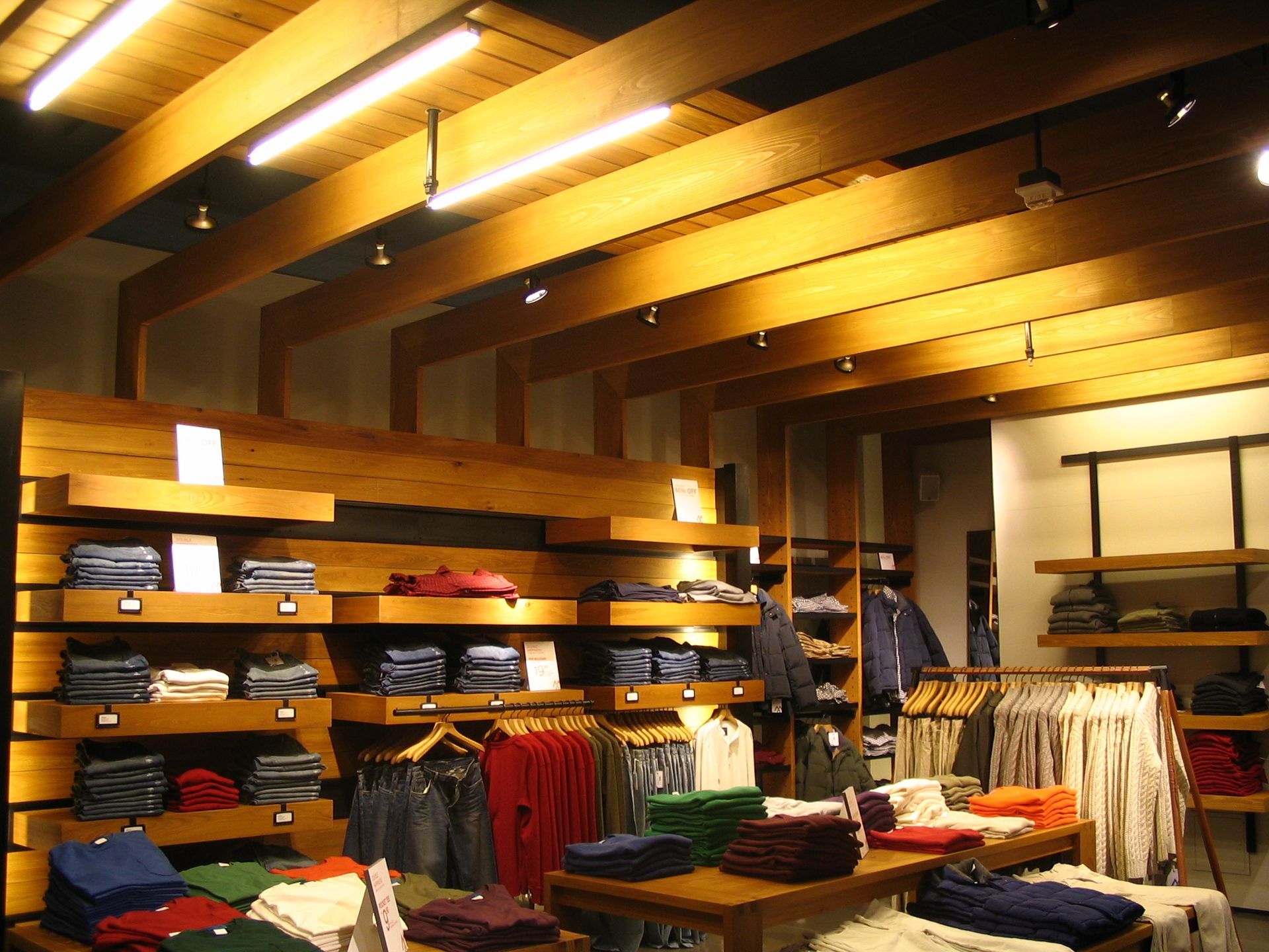 Wooden cabinetry in a kitchen area with a countertop, appliances, and a small bar with seating.